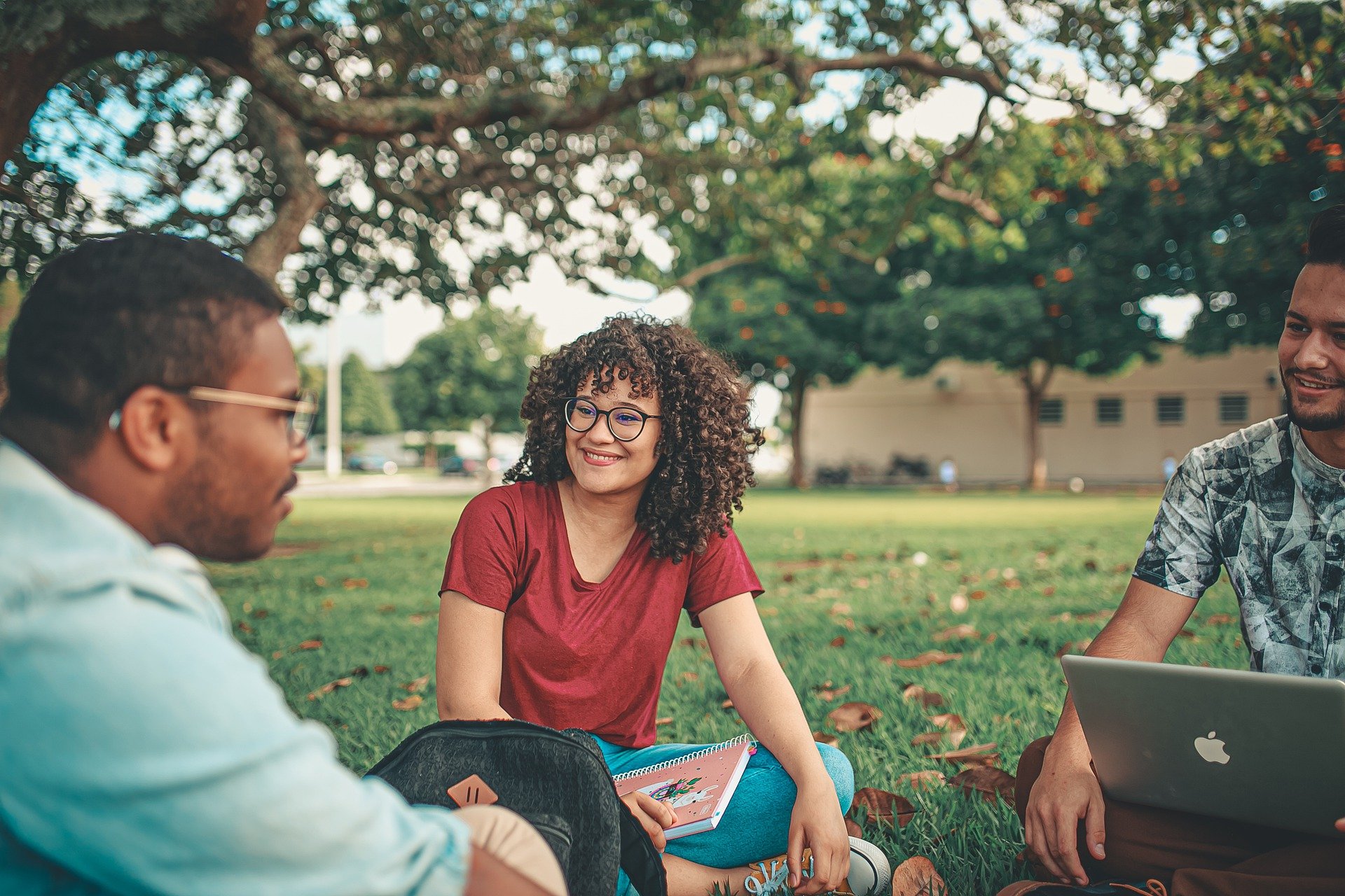 Three people sitting under a tree chatting