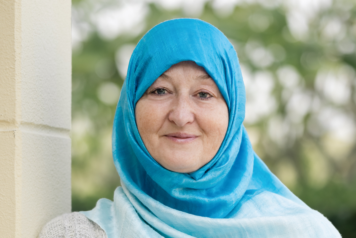 woman smiling at the camera with trees in the background