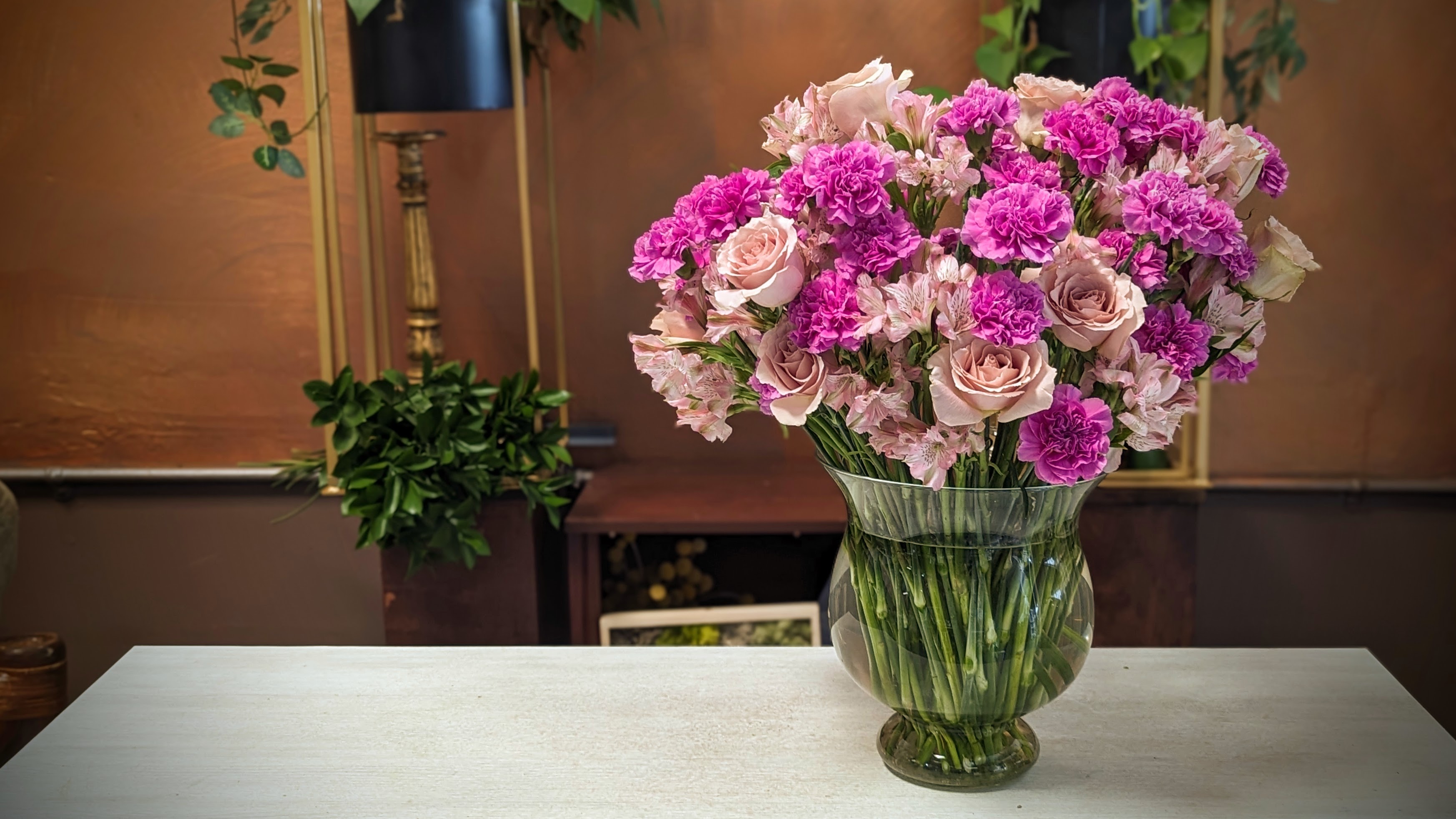 90 purple flower stems in a large glass vase