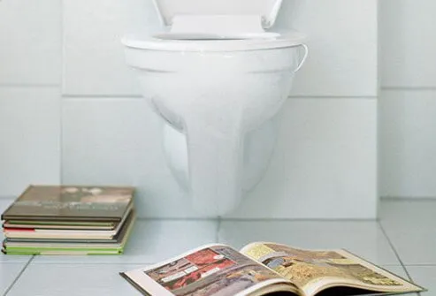 A toilet with books on the floor.