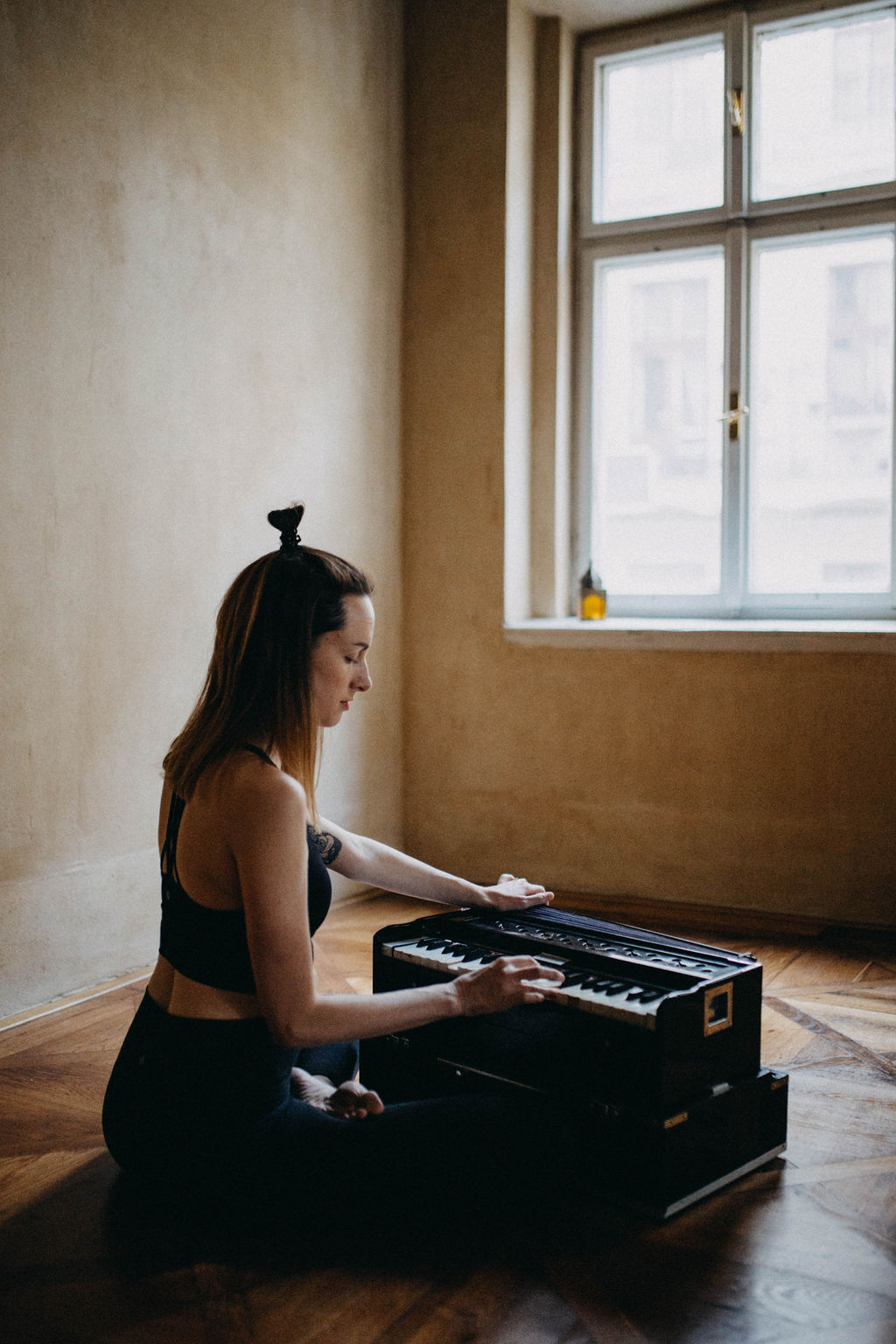 A woman playing harmonium near a window