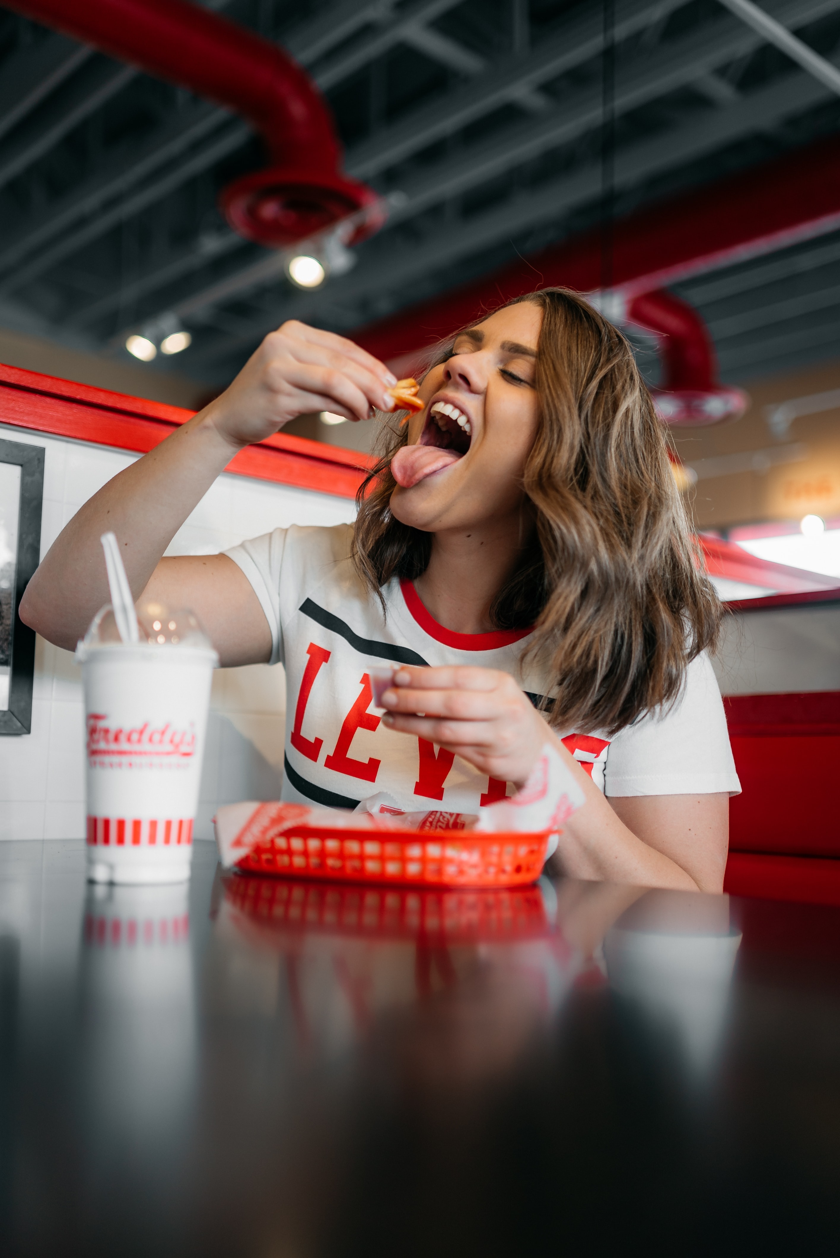 Woman eating french fries and vegan milkshake