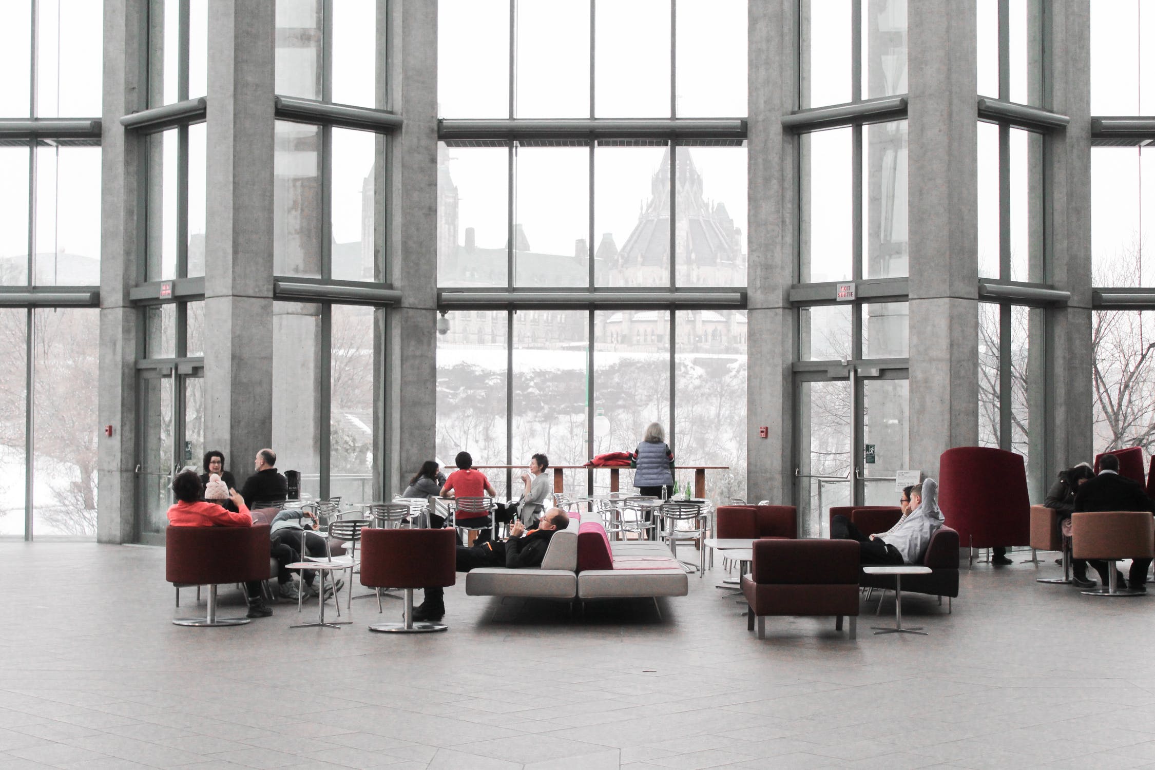 A gray office building interior with people collaborating at tables and on couches - photo credit Pexels, free to use in 