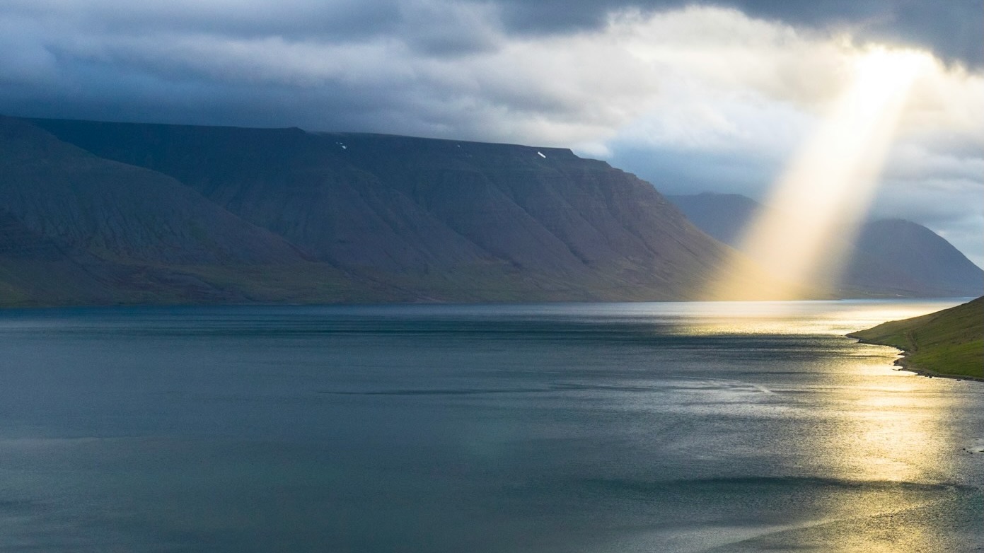 sunbeam through clouds onto water