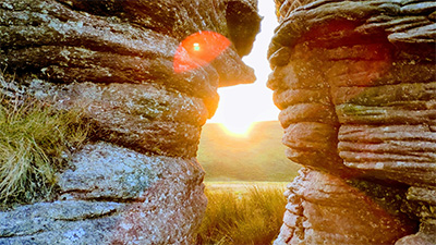 Sunlight shining through a gap in granite rocks on Dartmoor, UK, near where this course was filmed.