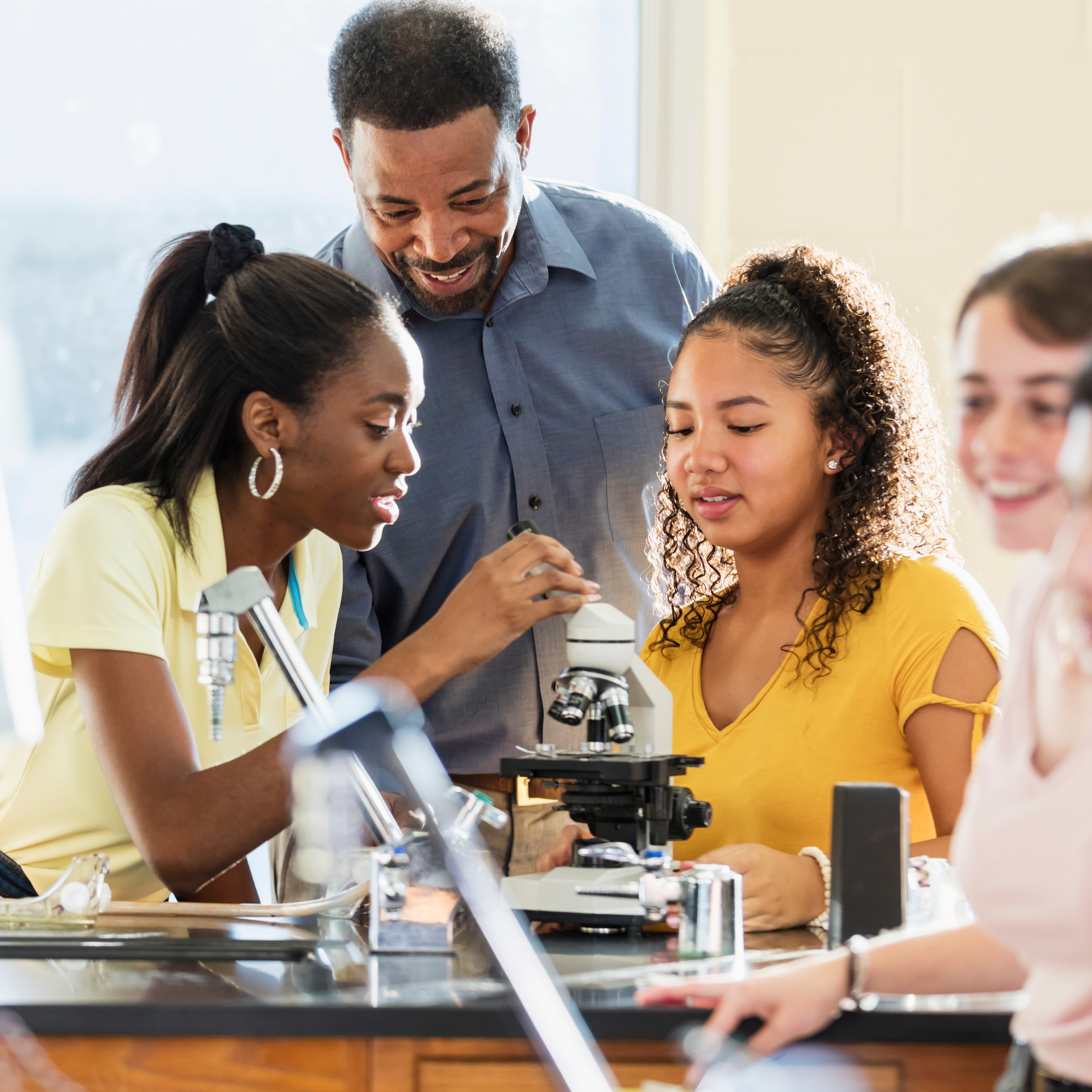 teacher working with students using microscopes