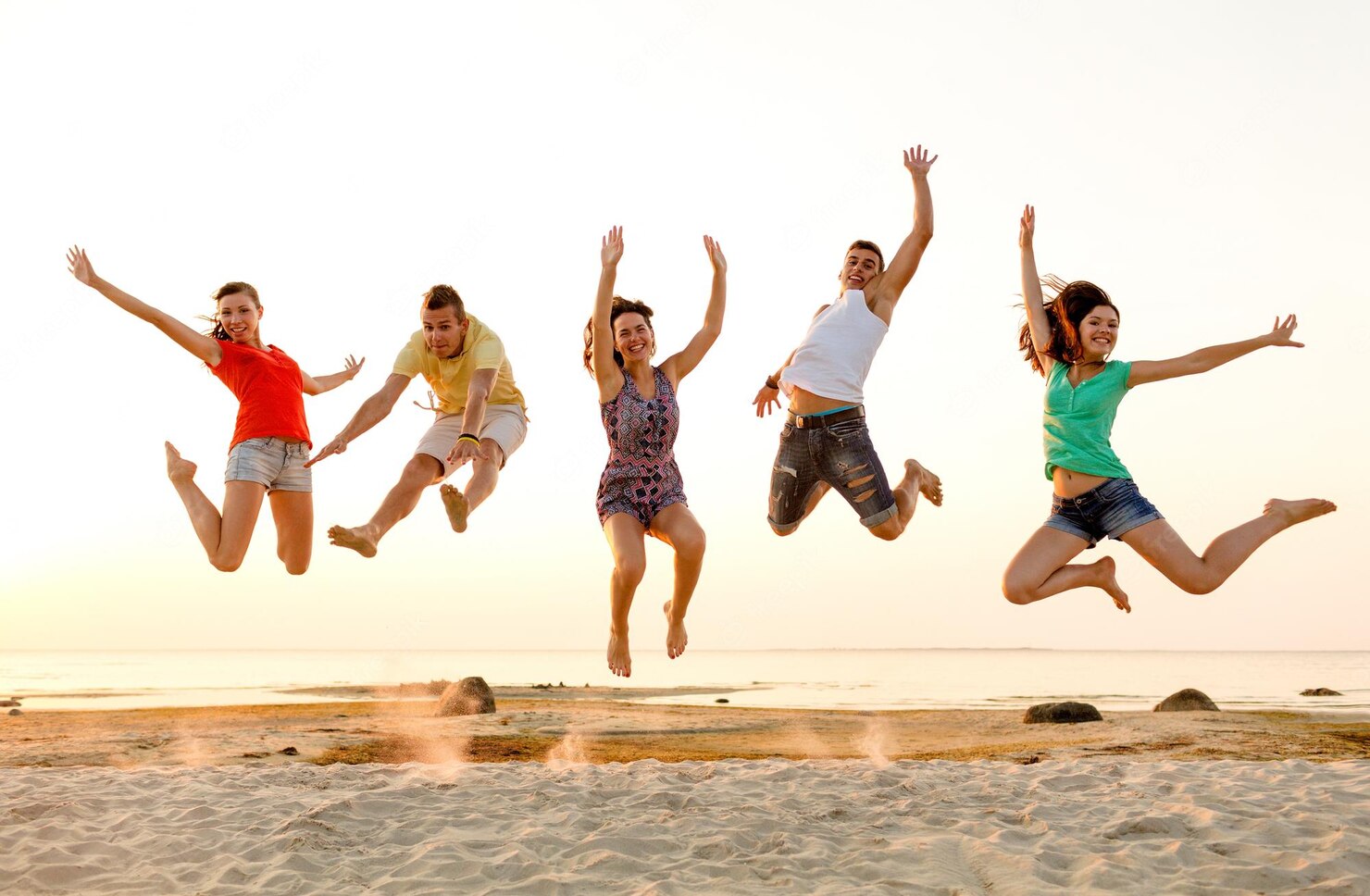 Happy and healthy people jumping at the beach