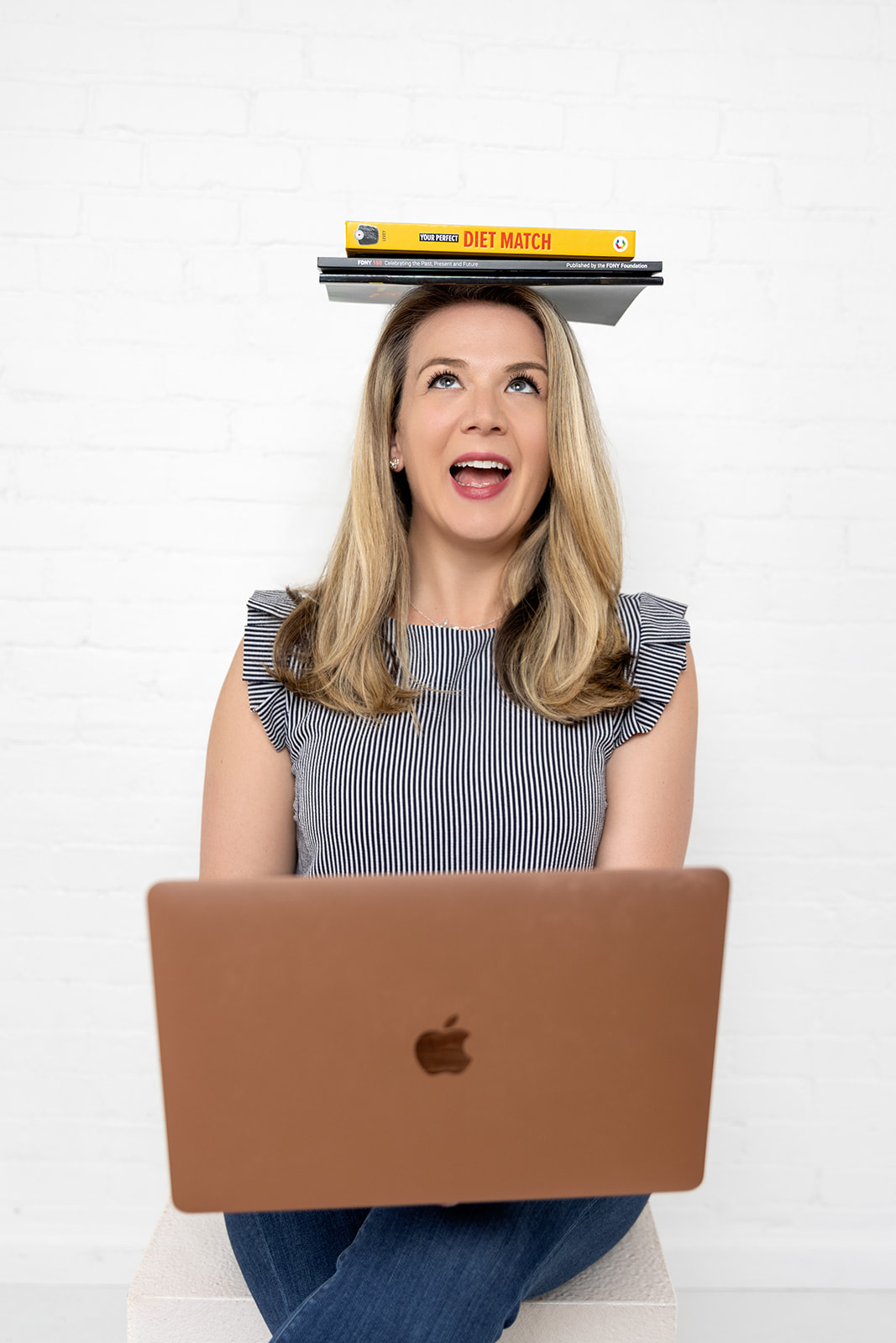 woman smiling with books on head