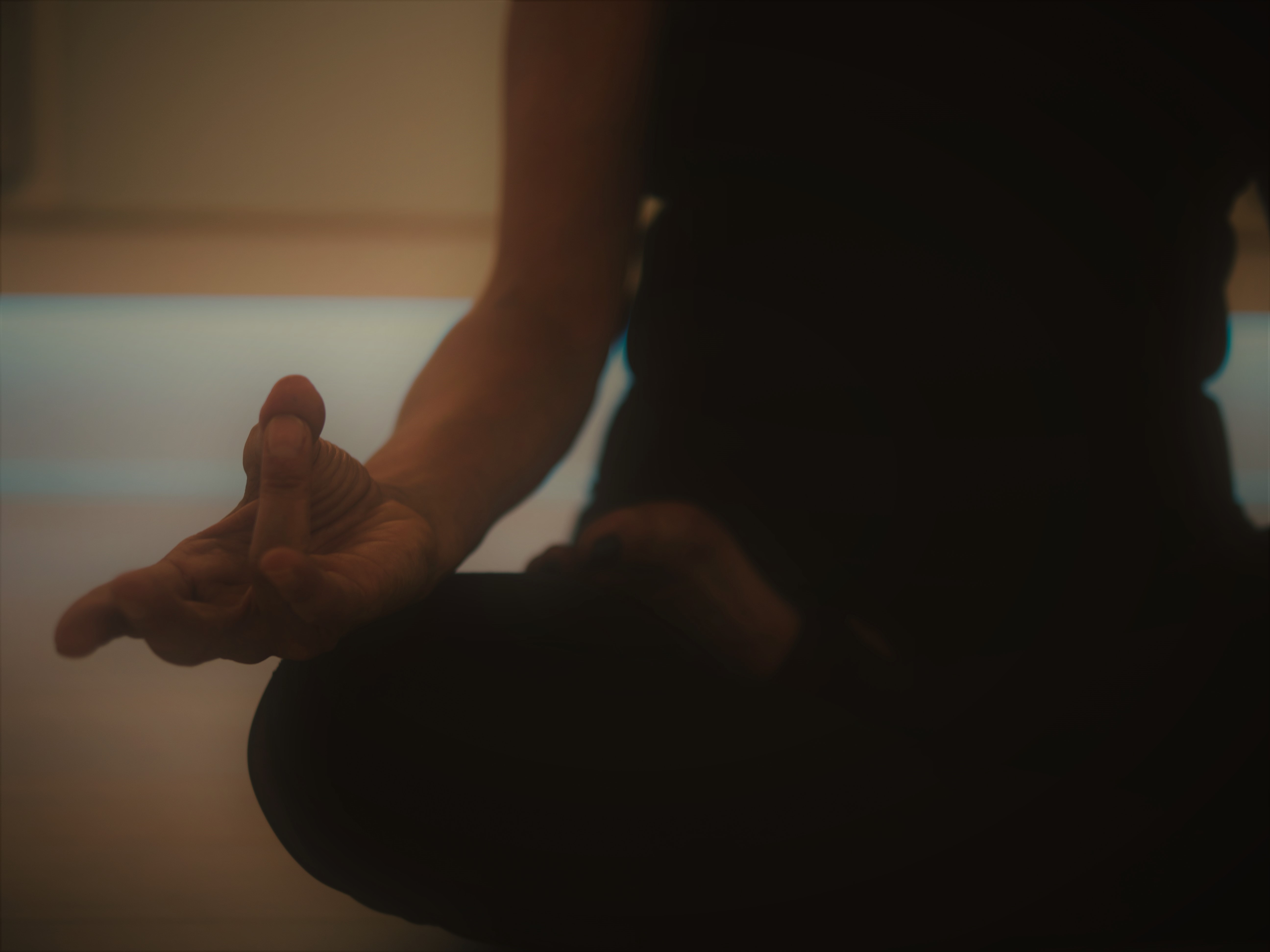 image of womans body sat on the floor in yoga lotus position,, with hand in a yoga mudra