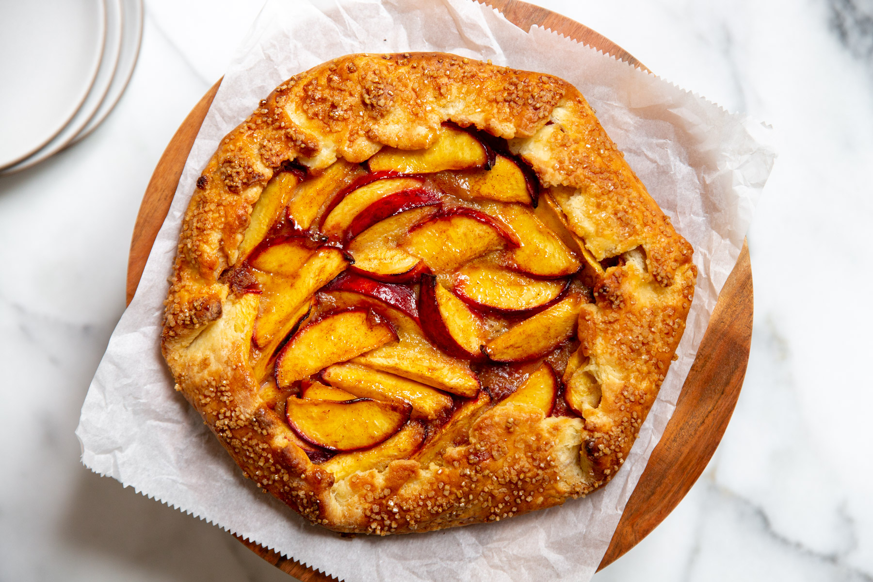 Peach almond galette in a pie stand.