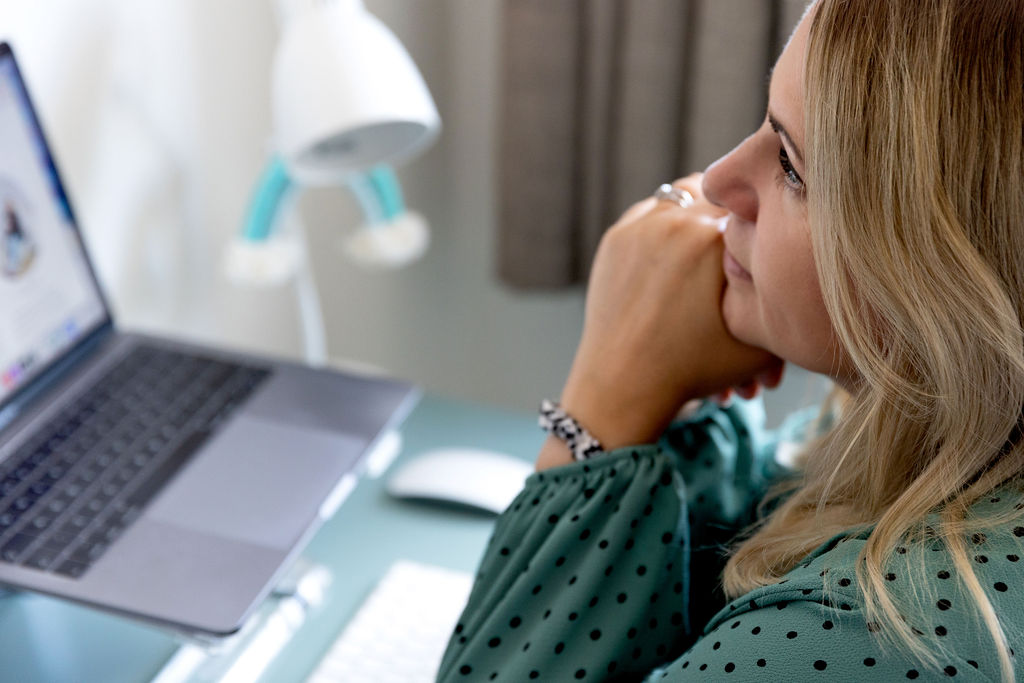 Emma thinking by laptop at desk