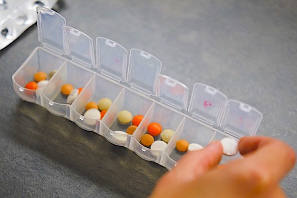 Person loading a medicine pill dosette box with tablets
