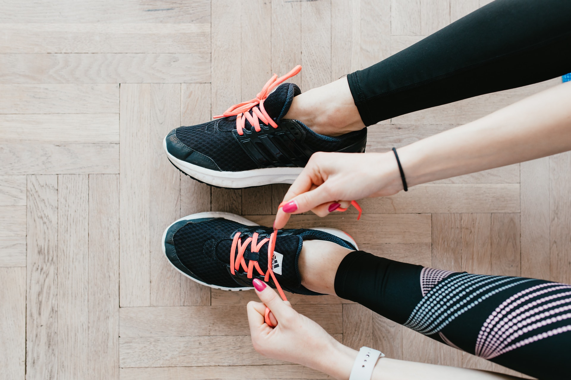 A person ties the laces of their black exercise shoes