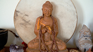 Wooden Buddha statue with prayer beads.