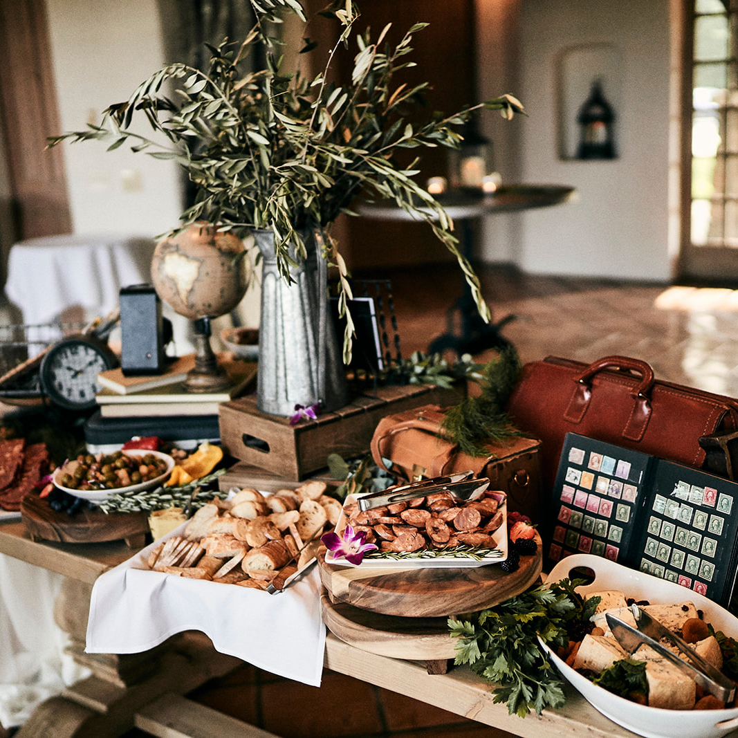 Tablescape with snacks, greenery, globe, clock, and luggage