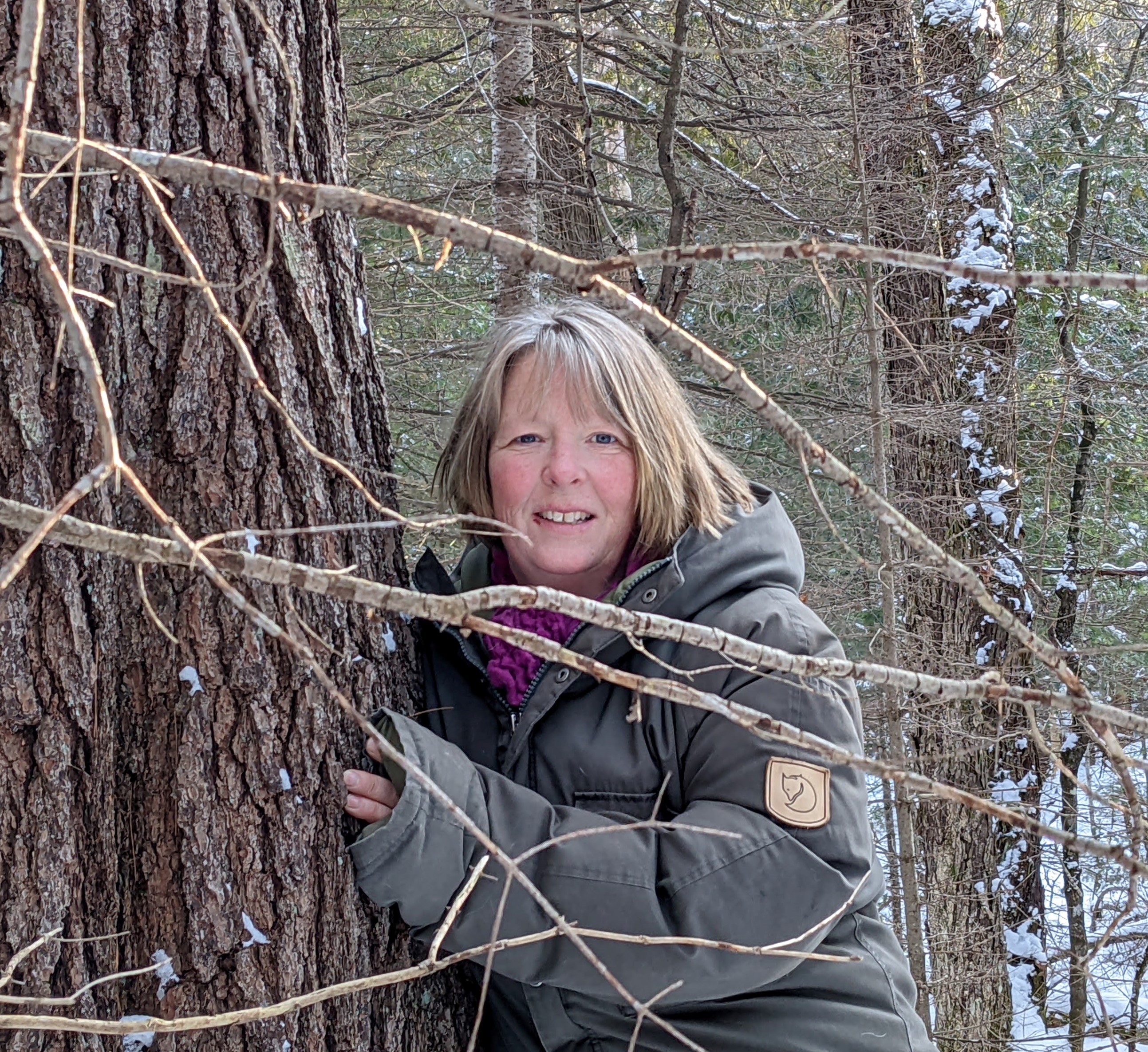 Tara Naylor hugging a pine tree