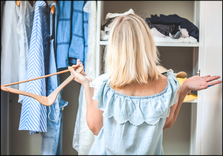 frustrated woman holding up her hands while standing in front of her closet