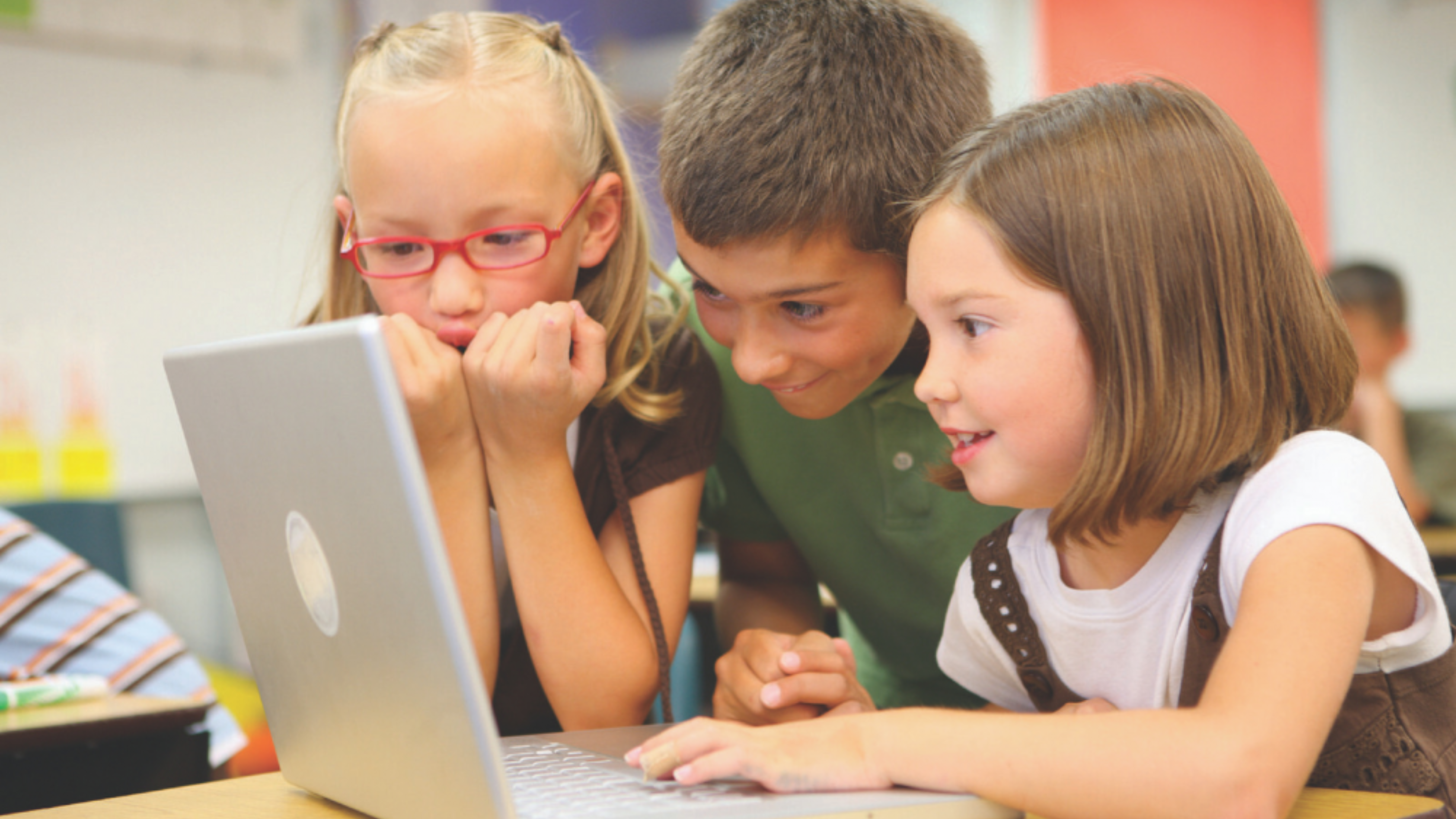 3 students looking at laptop smiling 