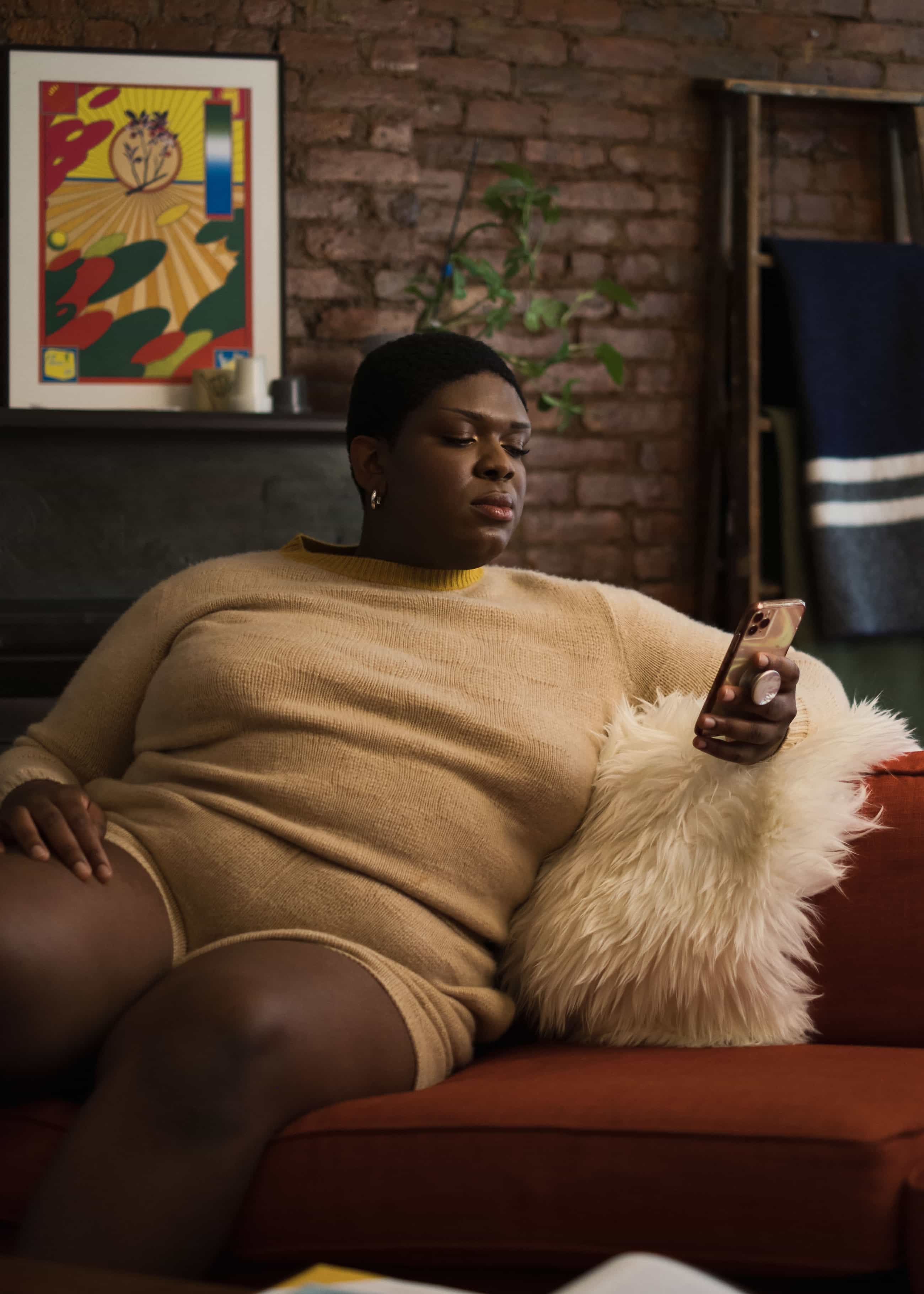 a non-binary Black woman looking down at a cell phone, source: https://genderspectrum.vice.com/