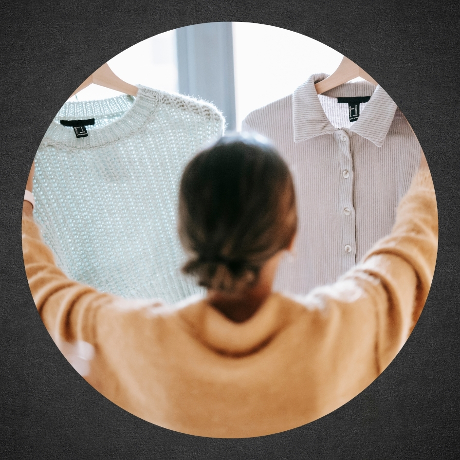 woman holding up two different shirts on hangers