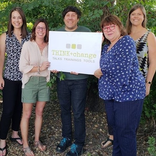 THINK+change team smiling and holding a THIKN+change sign. Pictured are 4 women and 1 man.