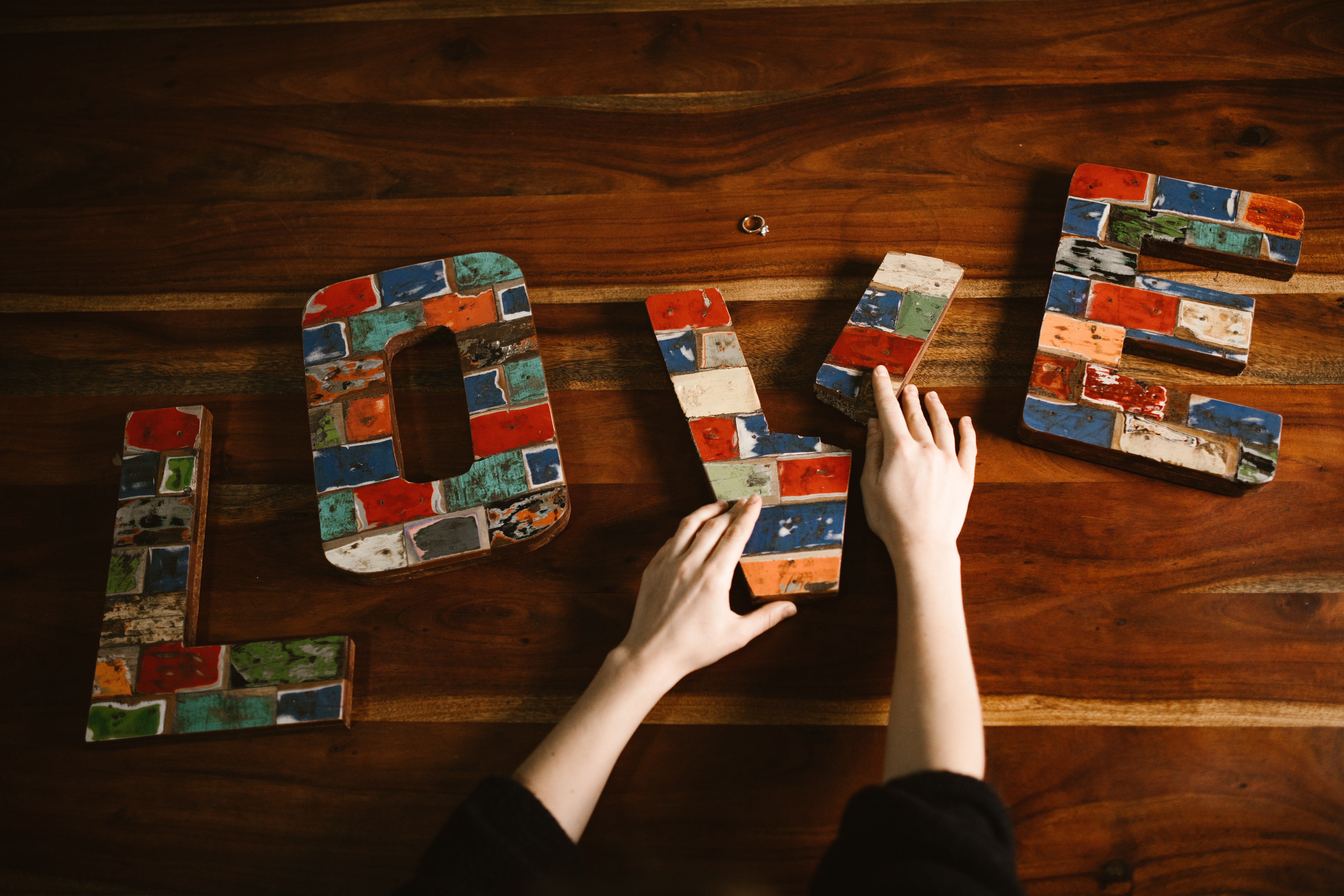 The letters L O V E are shown on top of a wood table, and a person