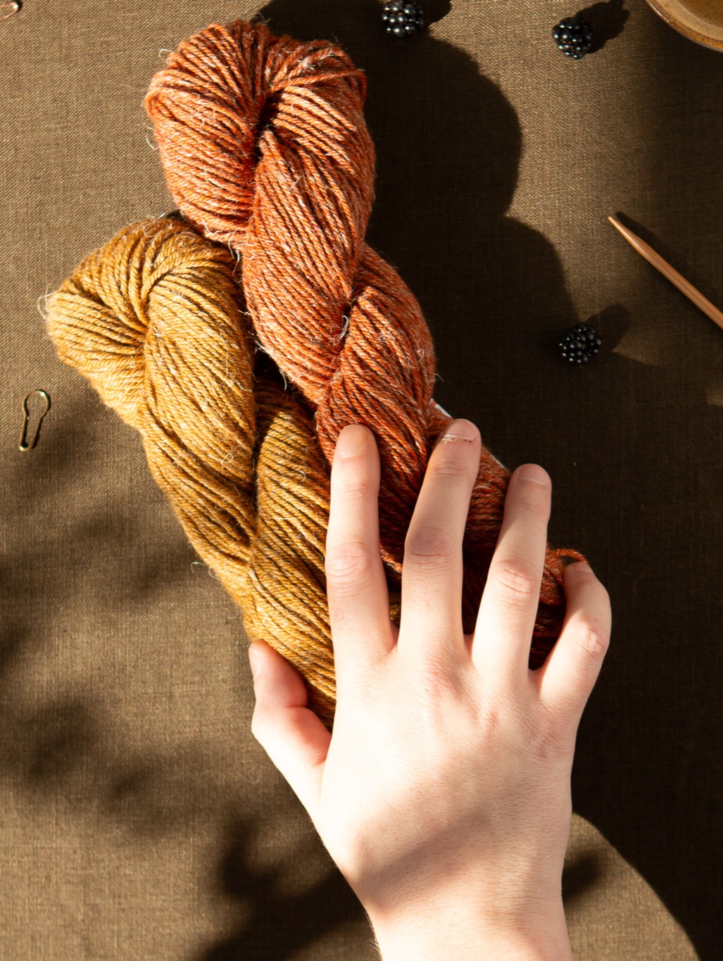 Autumn Seasons Yarn with hand holding two skeins.