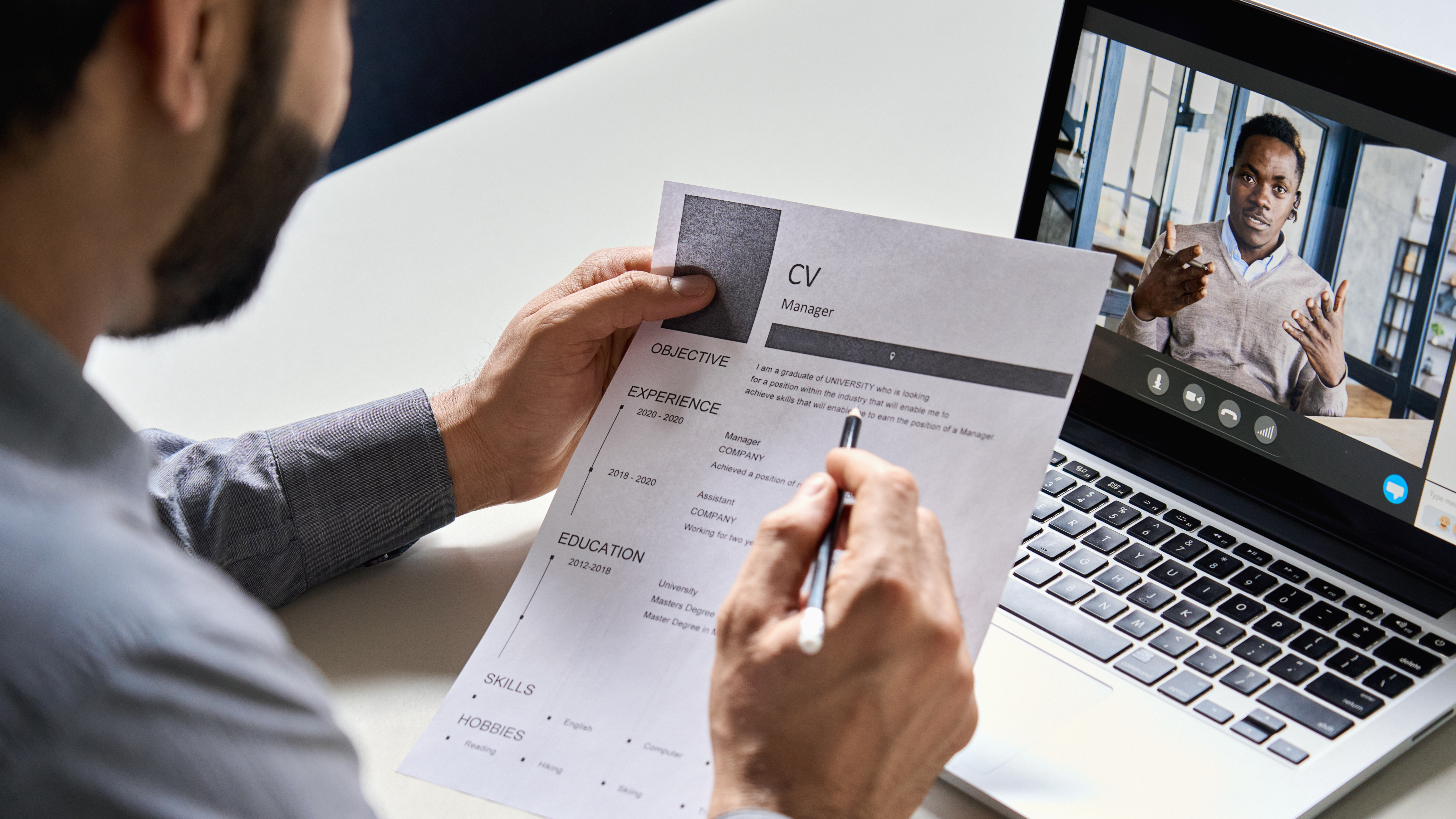 person looking over resume in front of laptop meeting