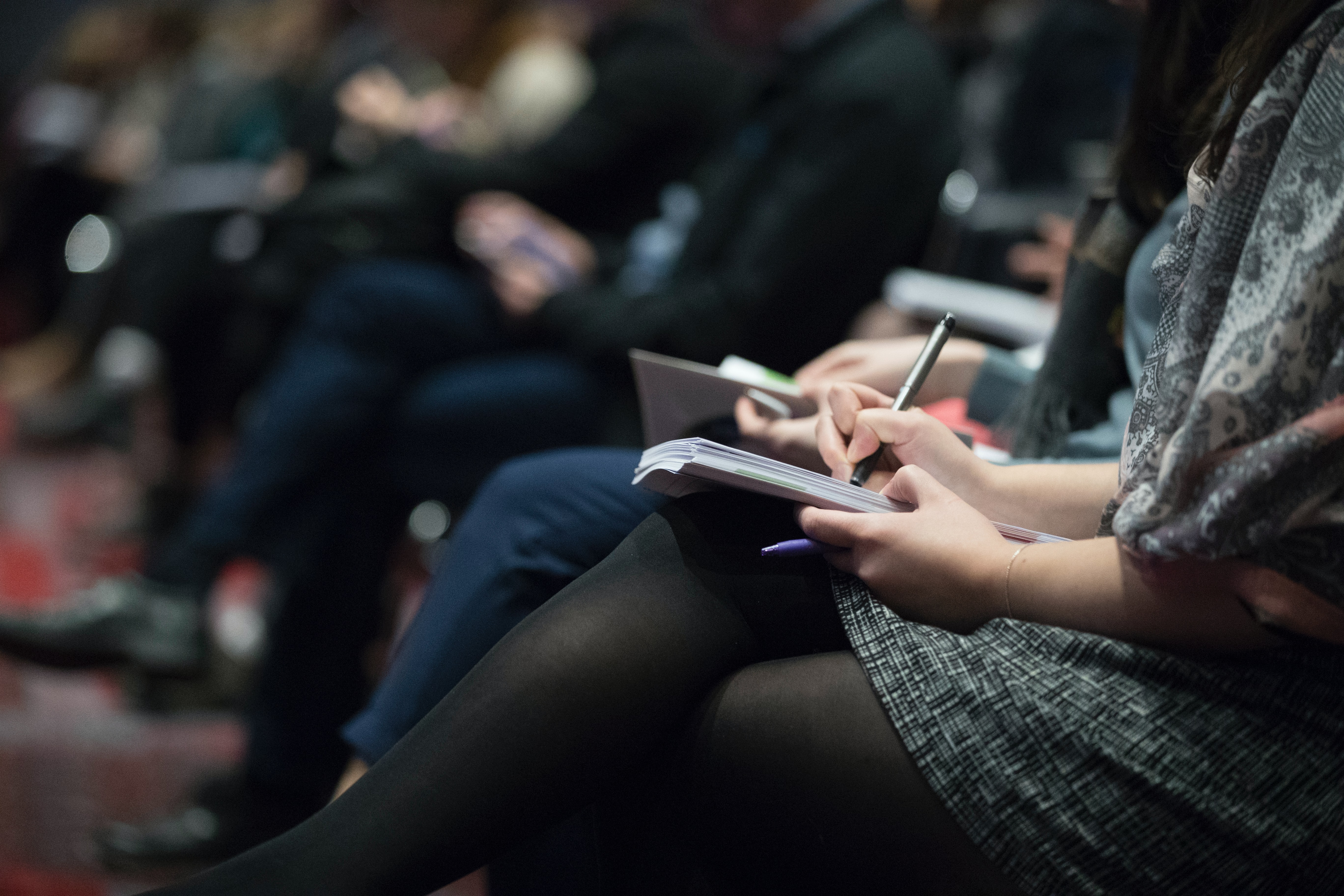 People sitting down and taking notes at a presentation