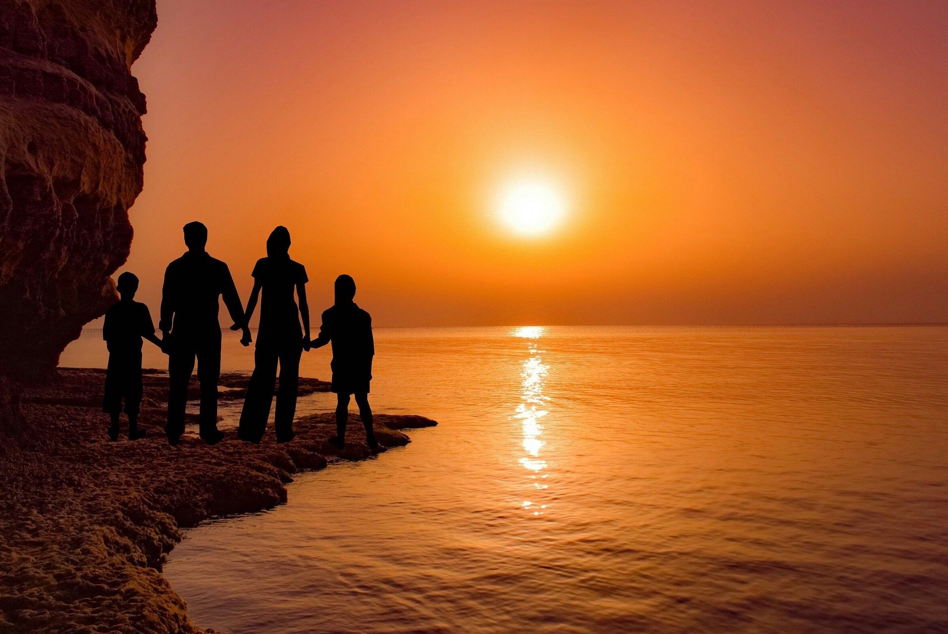 Family enjoying a beautiful sunset over water.