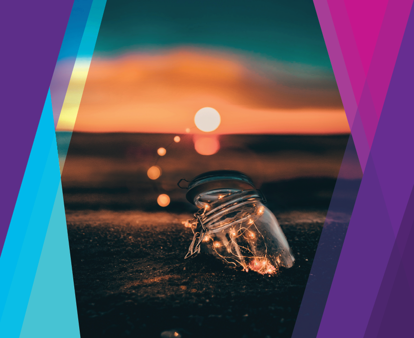 Lights inside of a glass jar resting on sand with the ocean in the background.