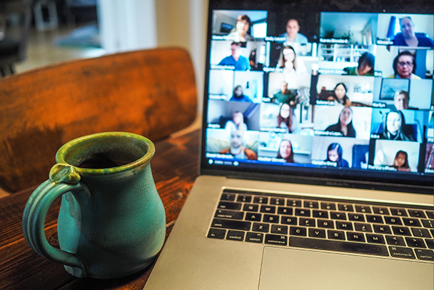 Una taza celeste al lado de una laptop.