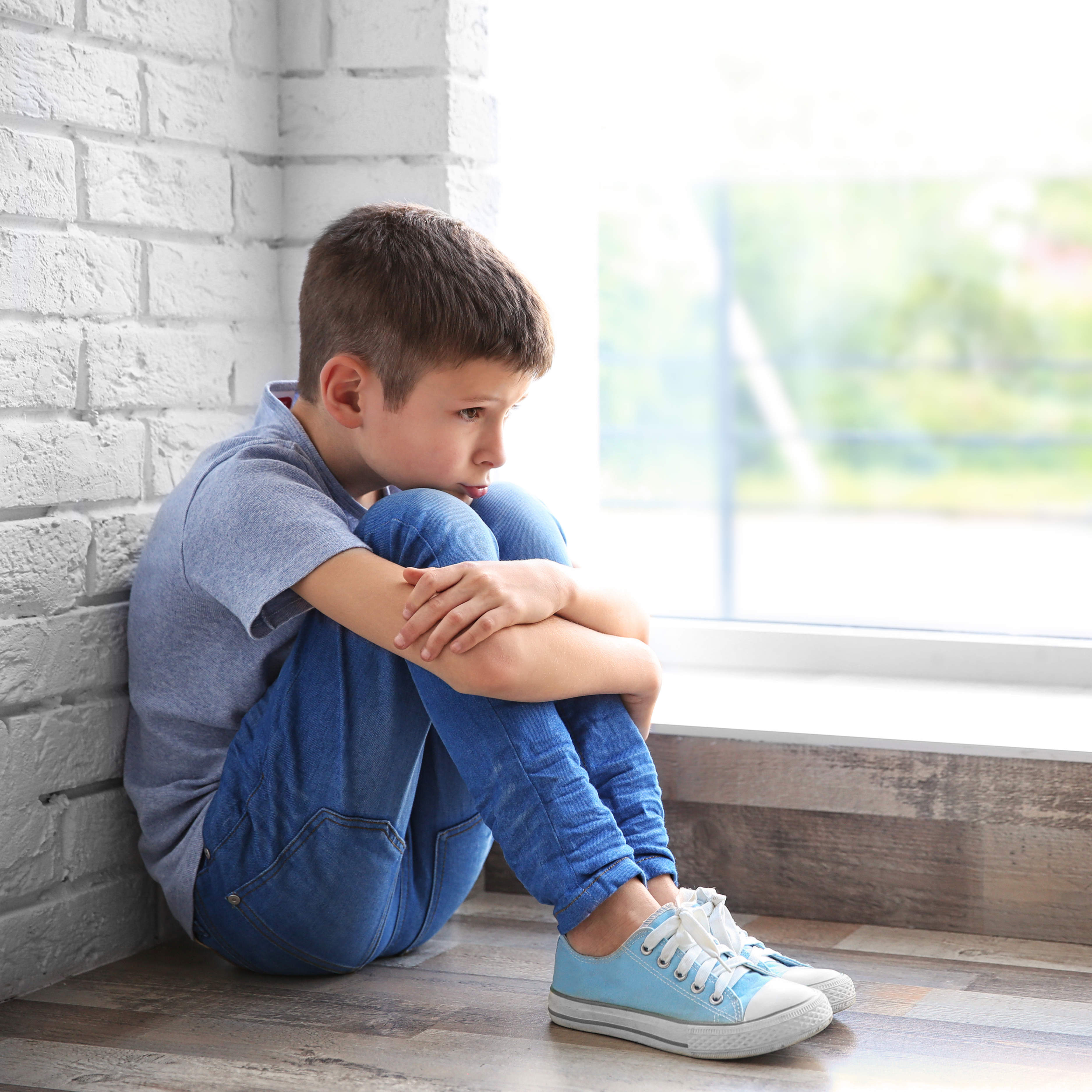 sad boy sitting in windowsill