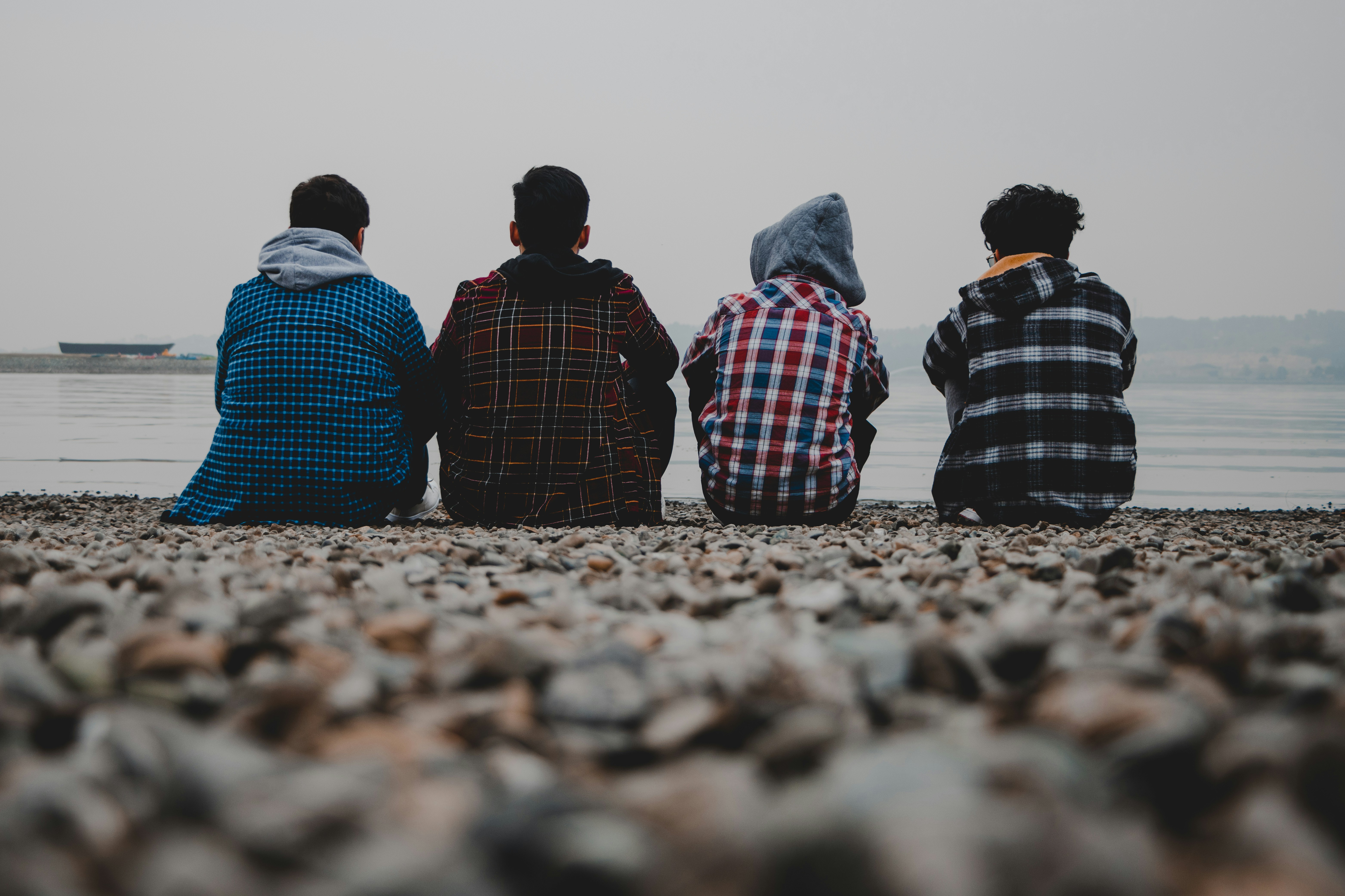 four people sitting on rocks at the edge of water