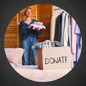 woman carrying folded clothes over to Donation box  on bed