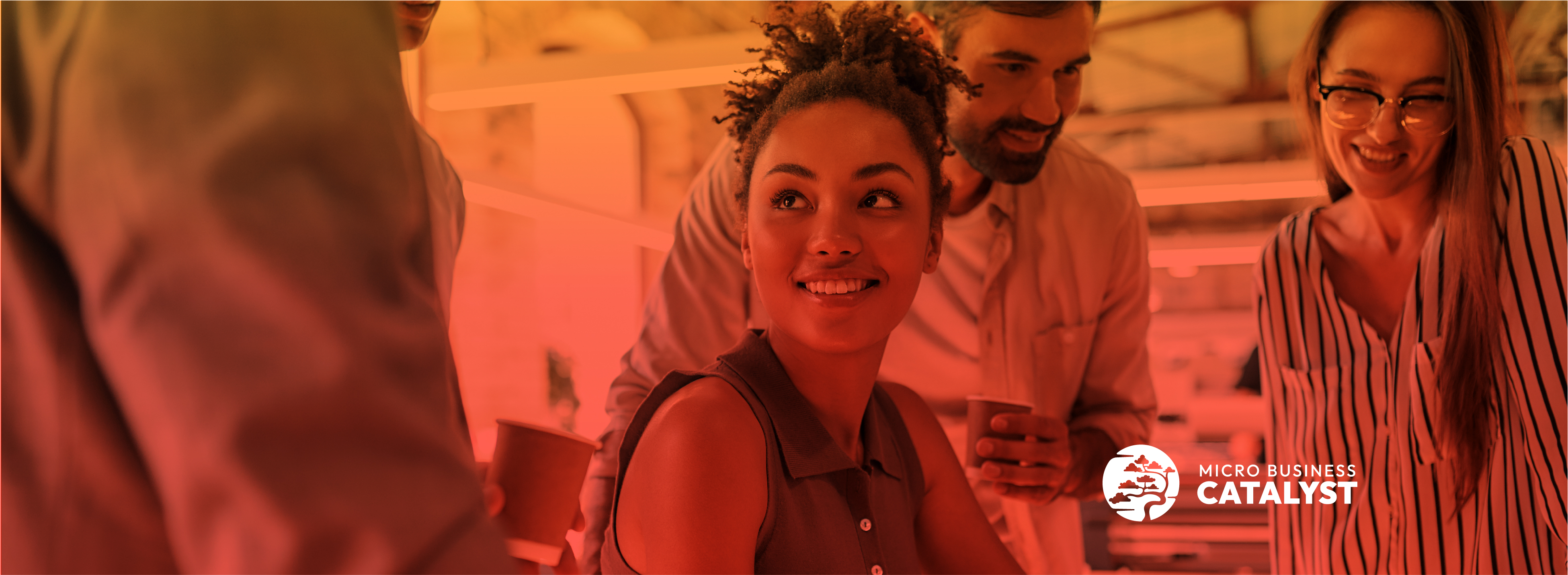 A group of diverse young professionals are smiling as the review meeting materials. A young black woman is in the center smiling and gazing at her teammates in the foreground.