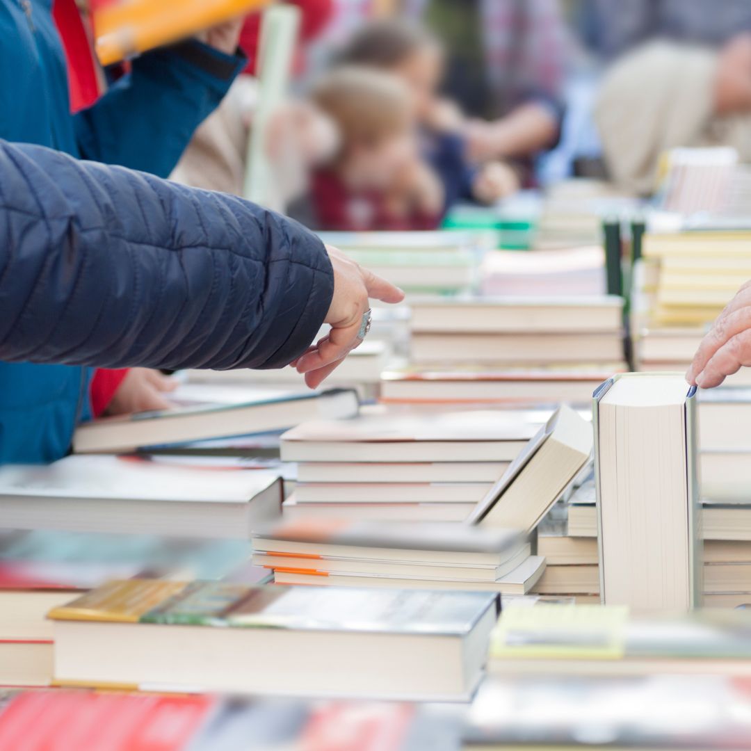 book sale with people pointing at books on table 