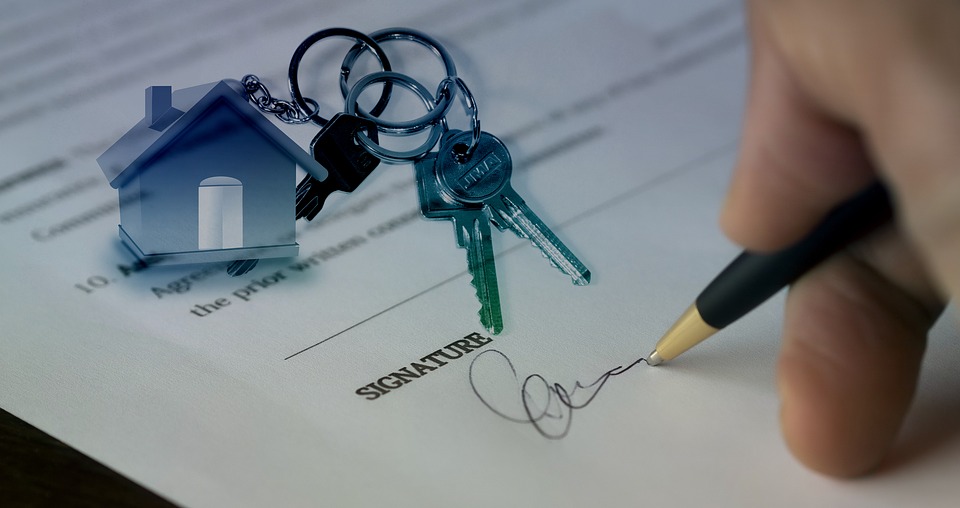 Person signing a document with keys and house