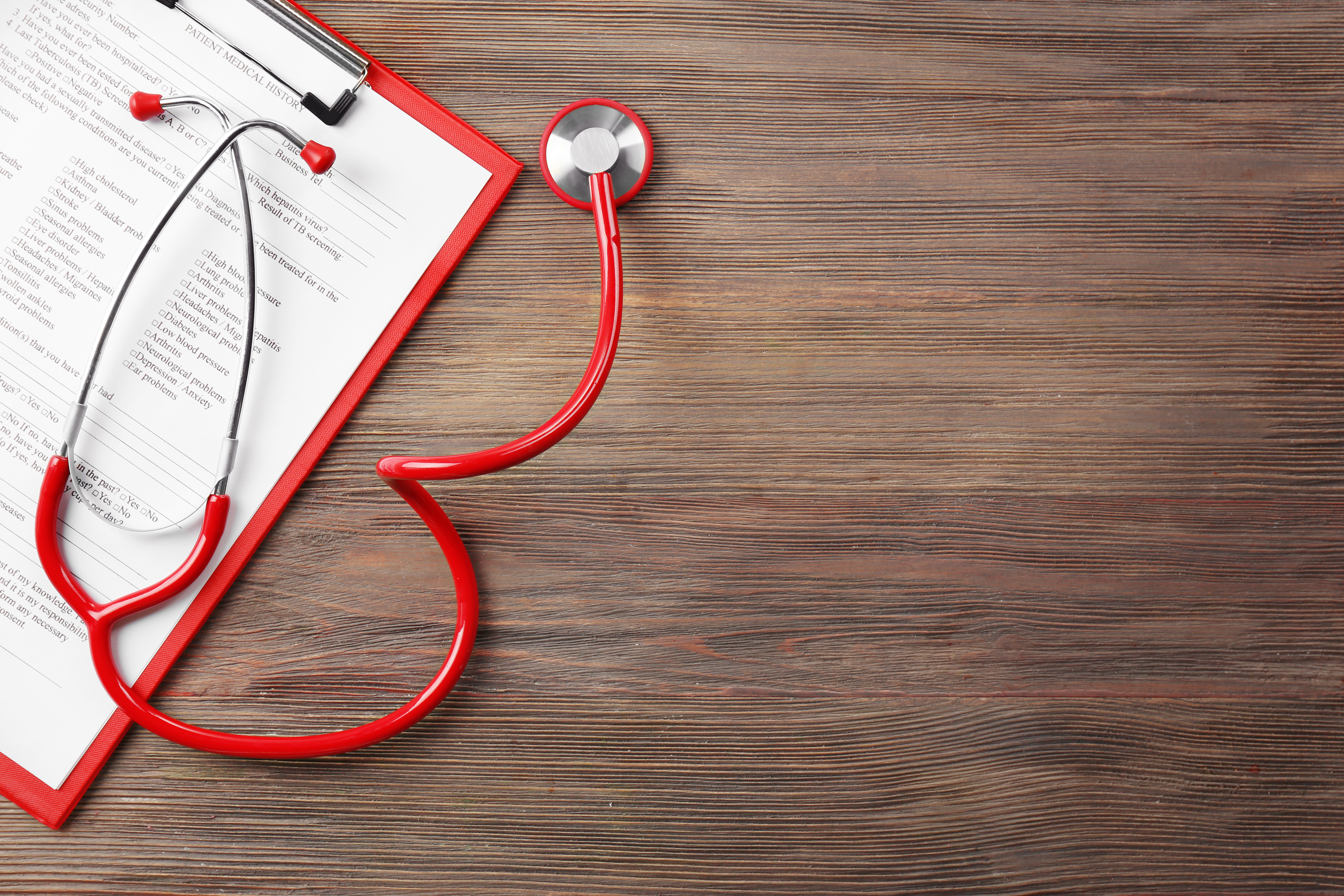 red clipboard with paper and red stethescope