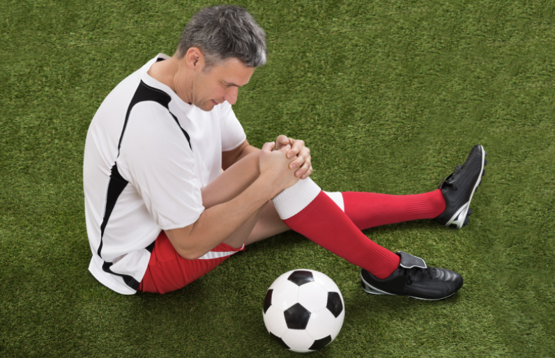 Soccer, football athlete holding his knee for minor muscular pain, or niggles.