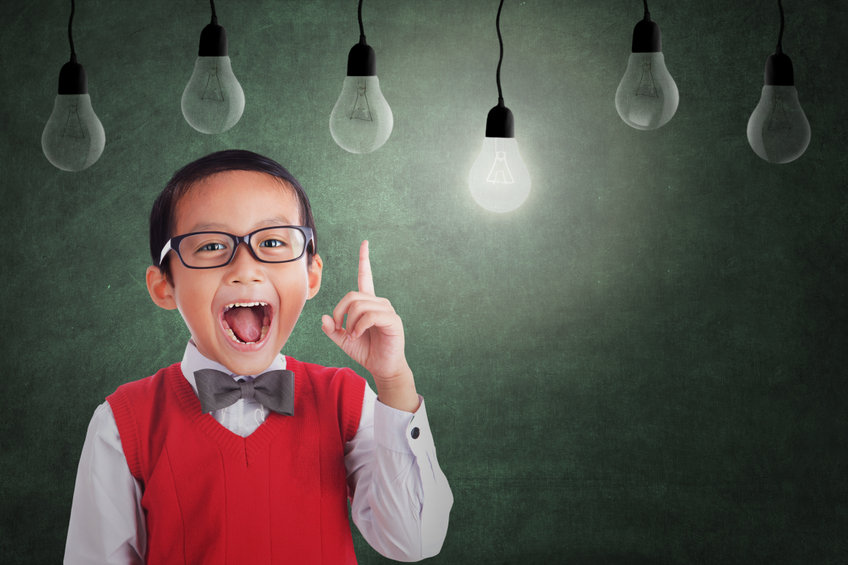 A little boy raising a finger with a lit lightbulb above him