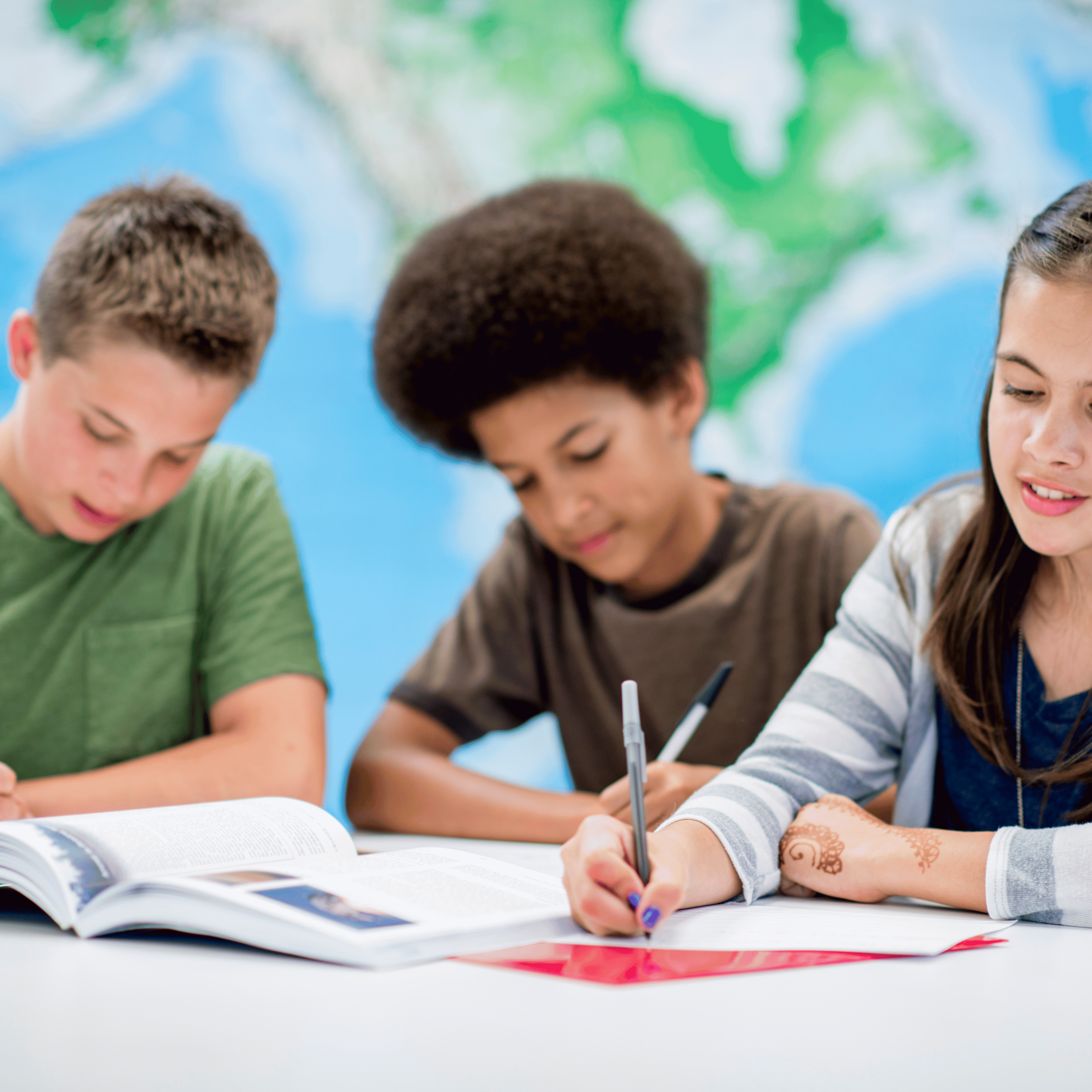 three students writing at desk