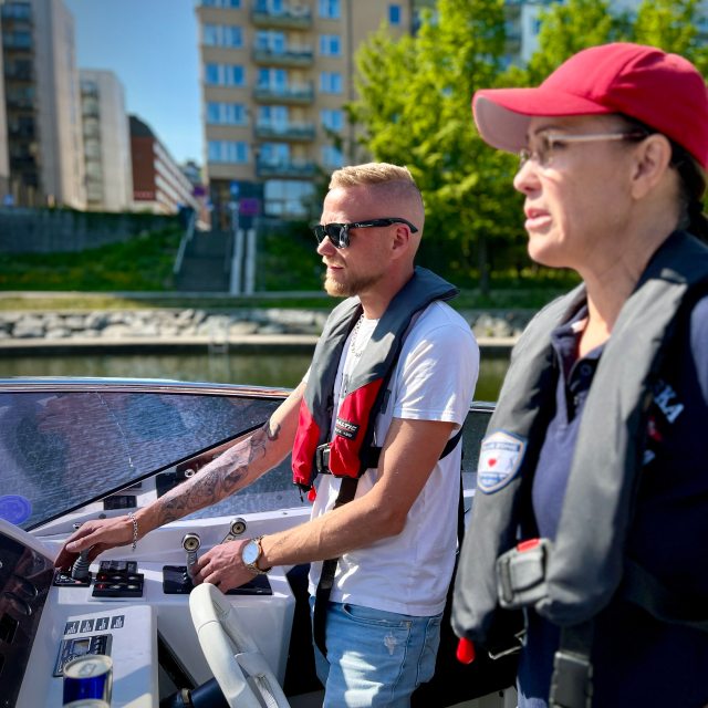 Man at the helm being coached by Maria Lannér in Stockholm City