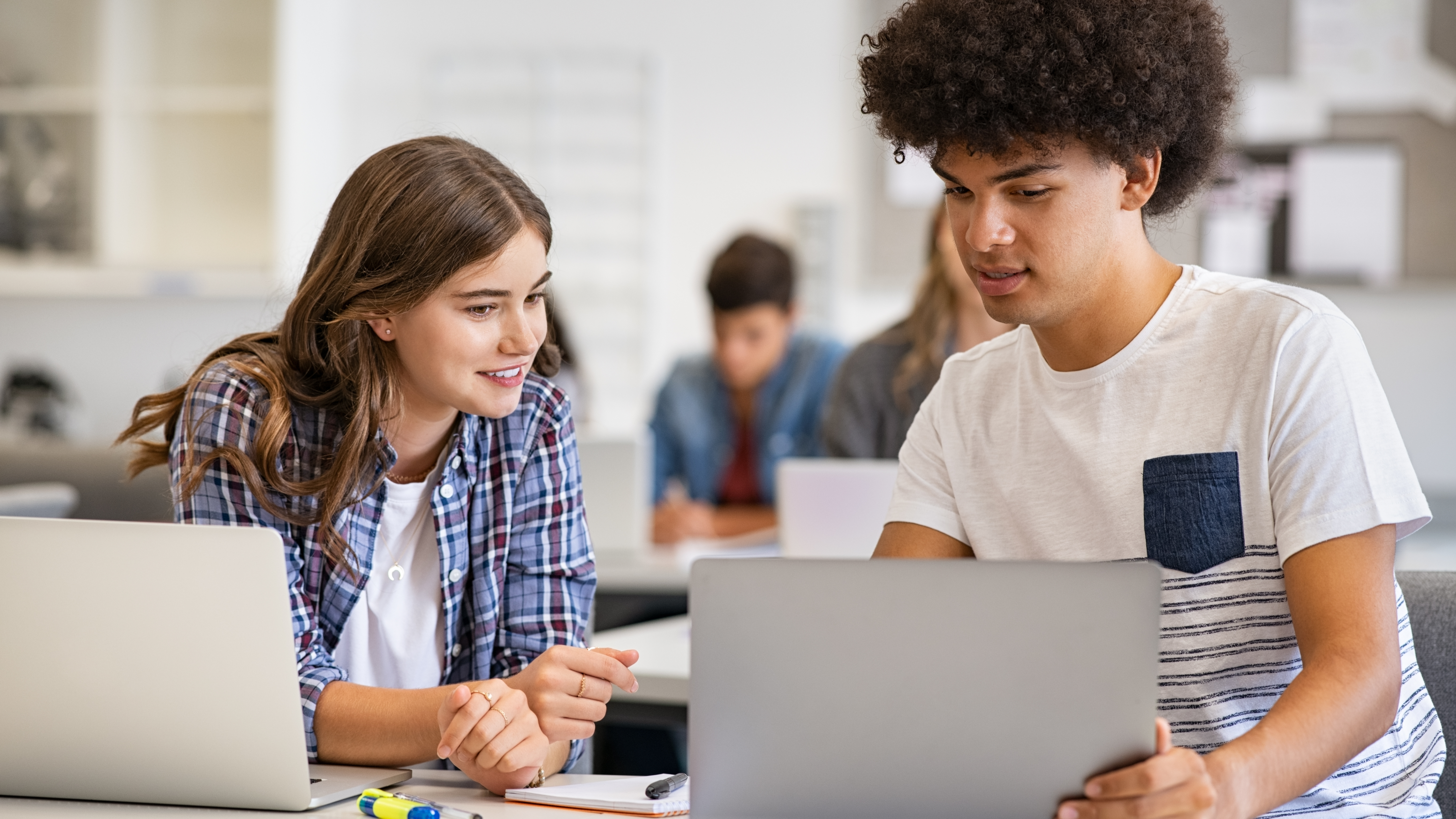 two students conferring using laptops