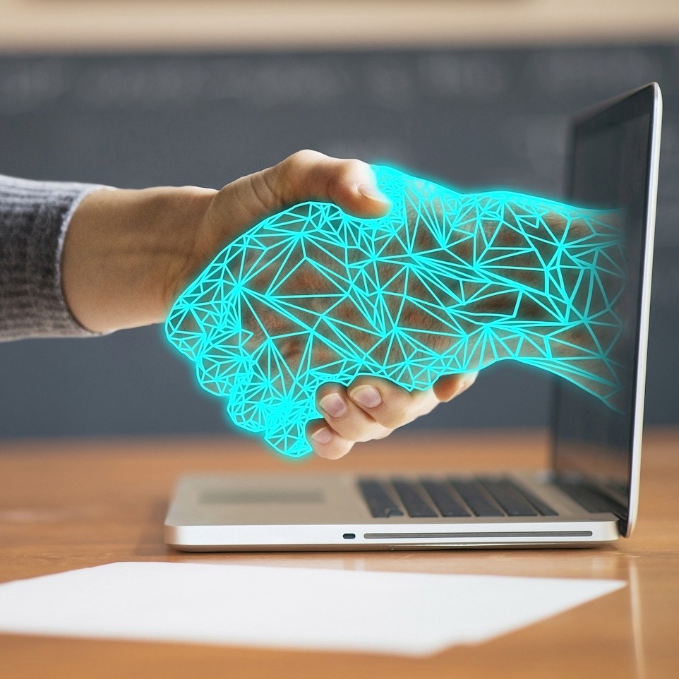 Person shaking an electronic hand out of a computer screen