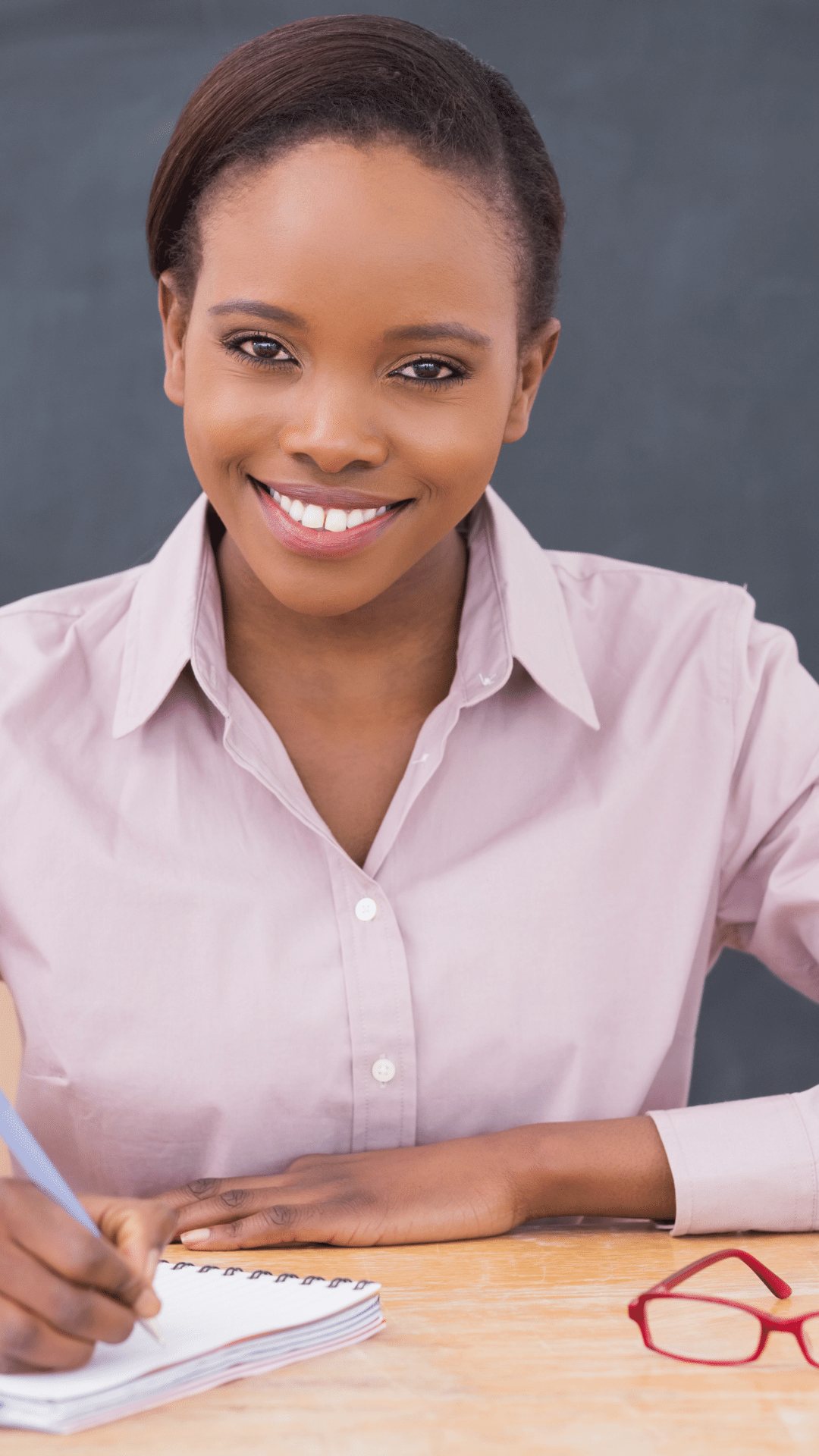 Smiling woman with a pen and notebook.