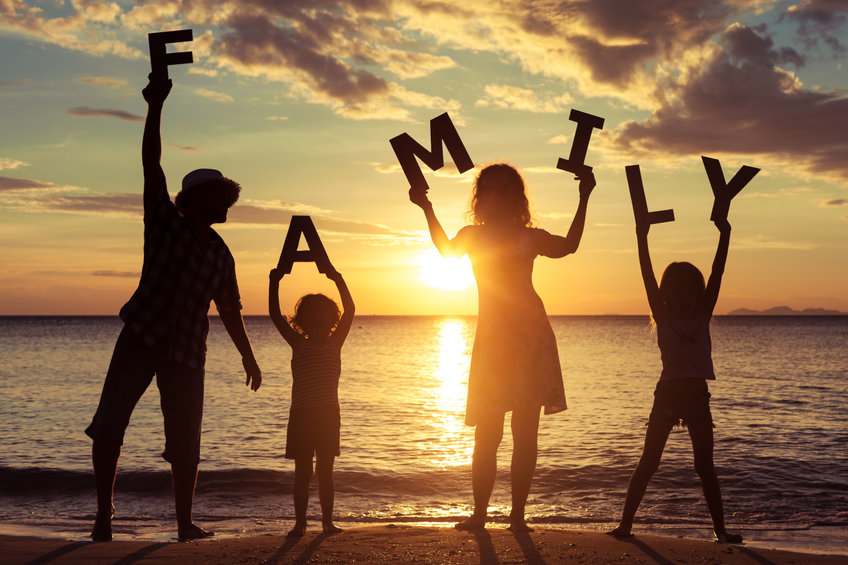 family members holding up letters spelling family in sunset