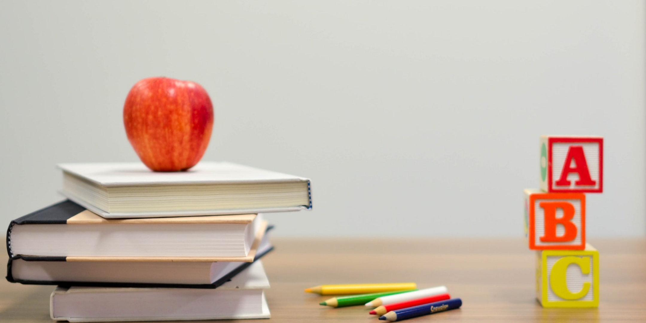 Apple, books, and ABC blocks on a wooden table