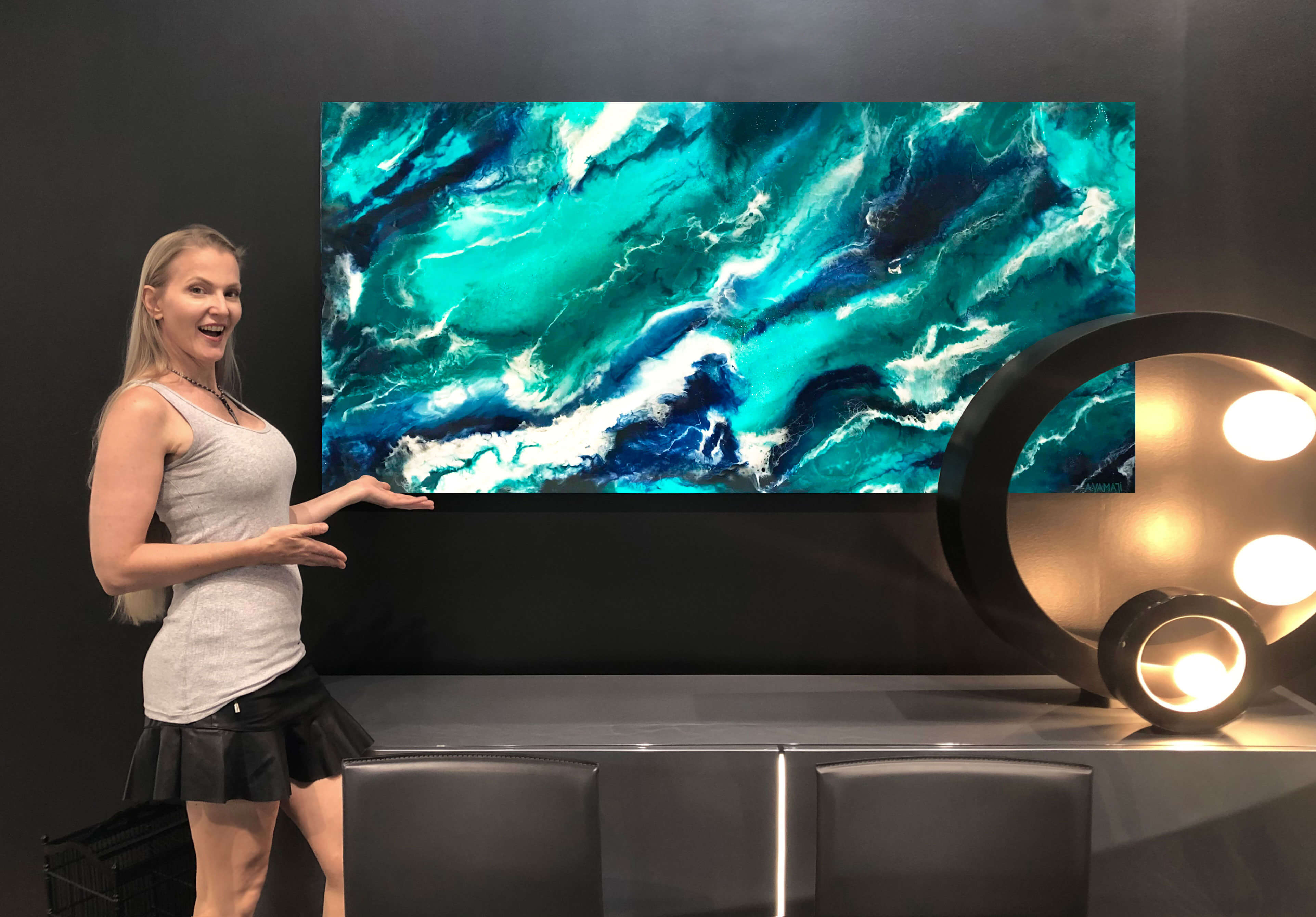 Anja Yamaji standing in front of a large resin art painting exhibited for sale at Roche Bobois, a designer furniture store, showcasing the unique style and creativity taught in her resin art workshop.