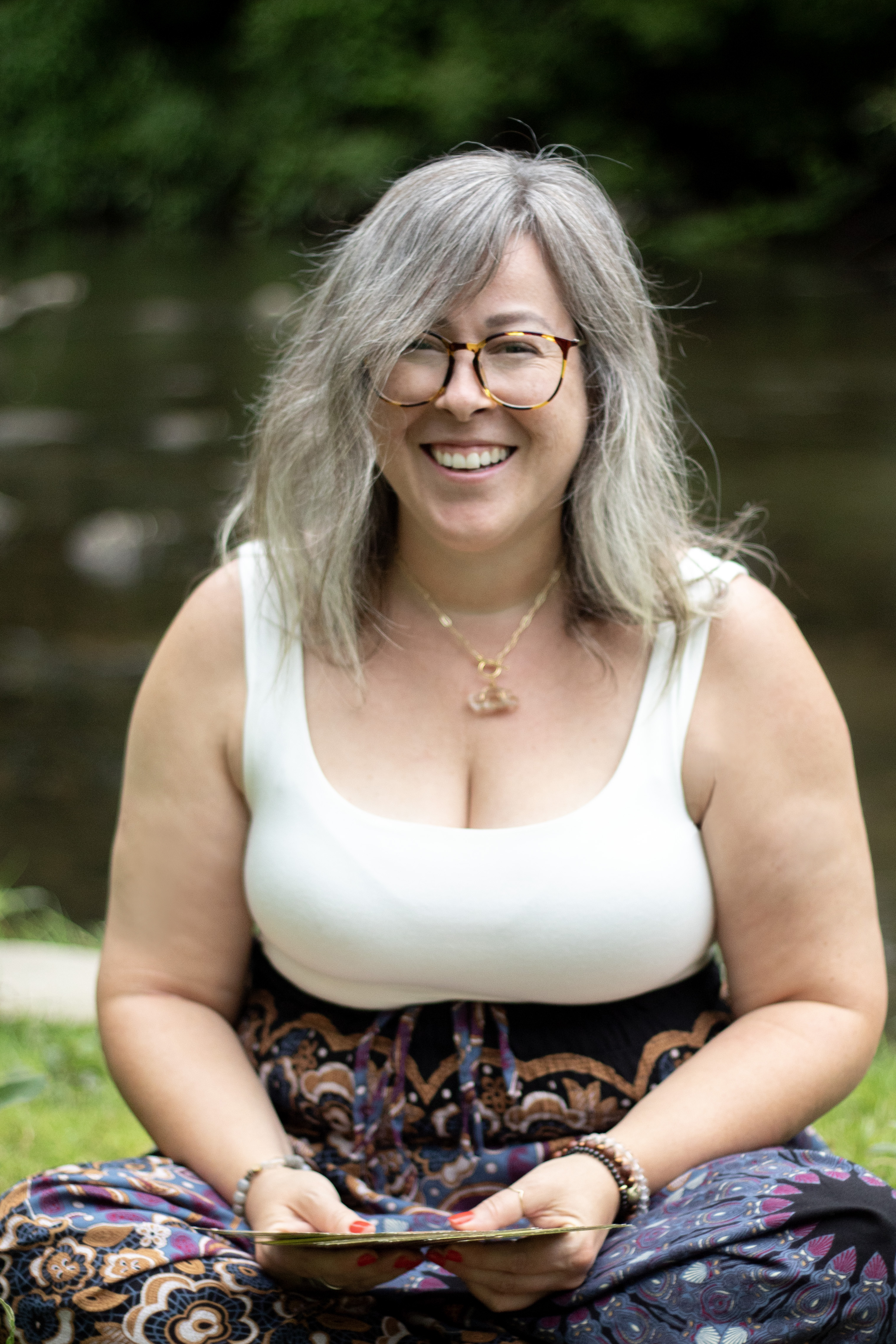 Woman holding tarot cards outside by water